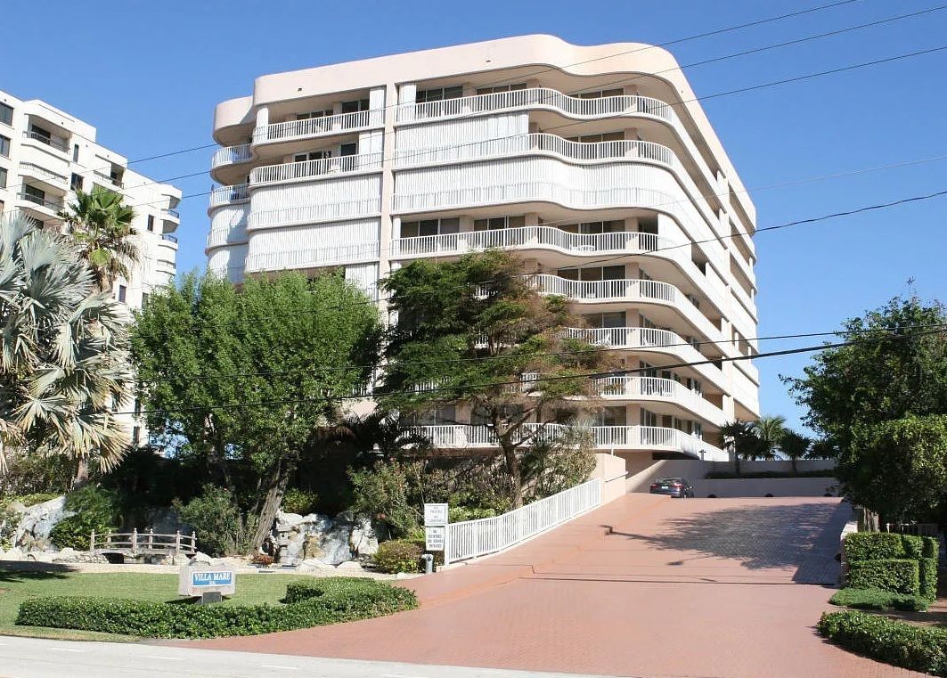 A large building with a lot of windows is surrounded by trees and bushes