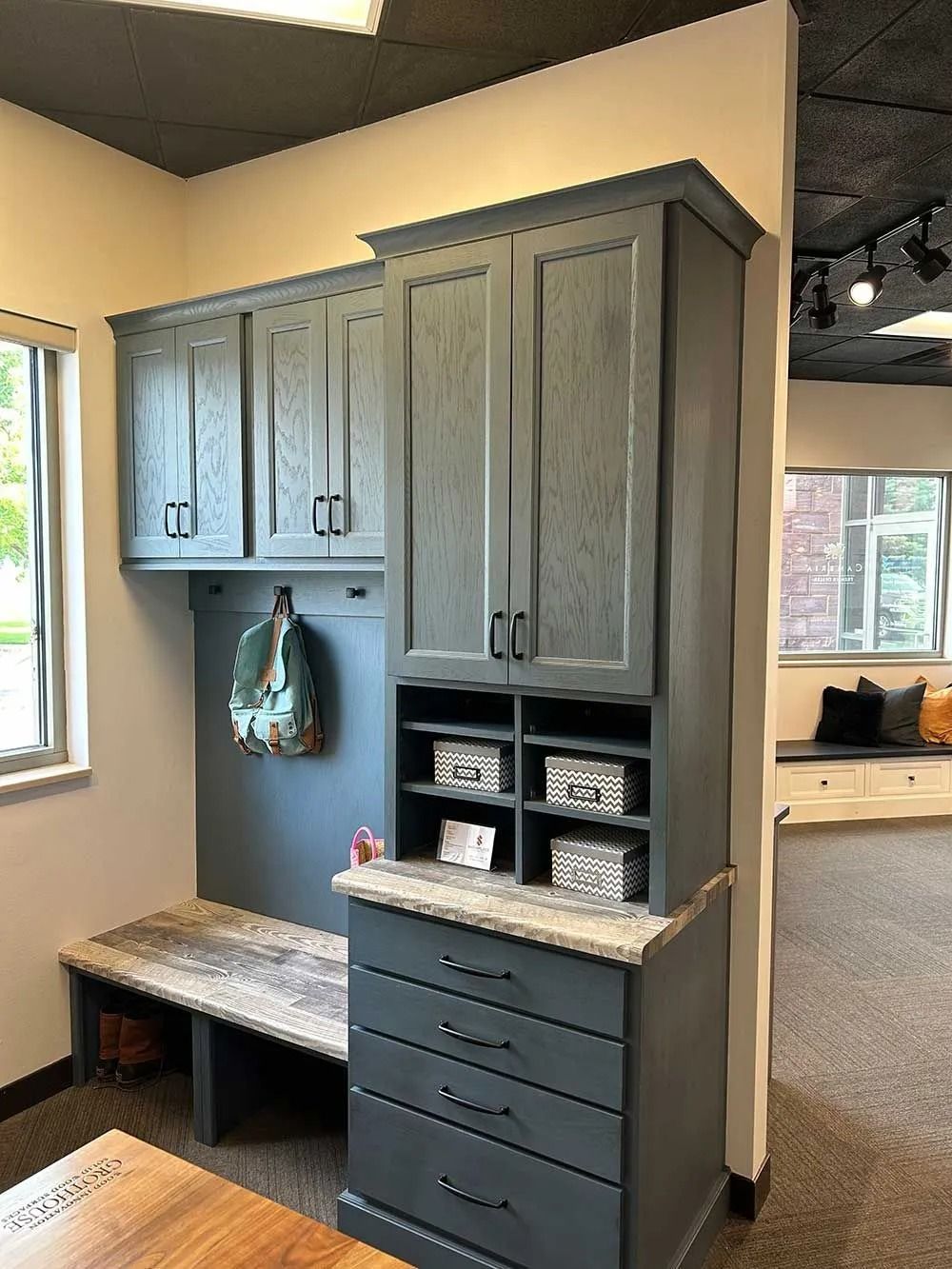 A mudroom built-in with a dark gray cabinet, drawers, and bench seating with a stone-look countertop.