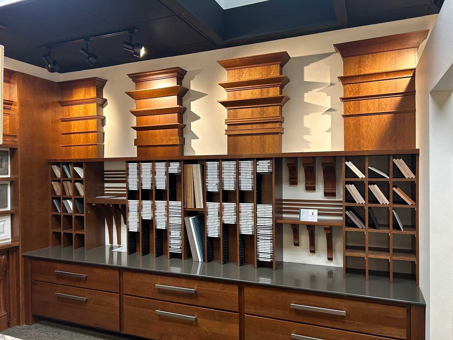 Wood shelving unit featuring various crown molding styles, architectural corbels, and storage drawers in a showroom.