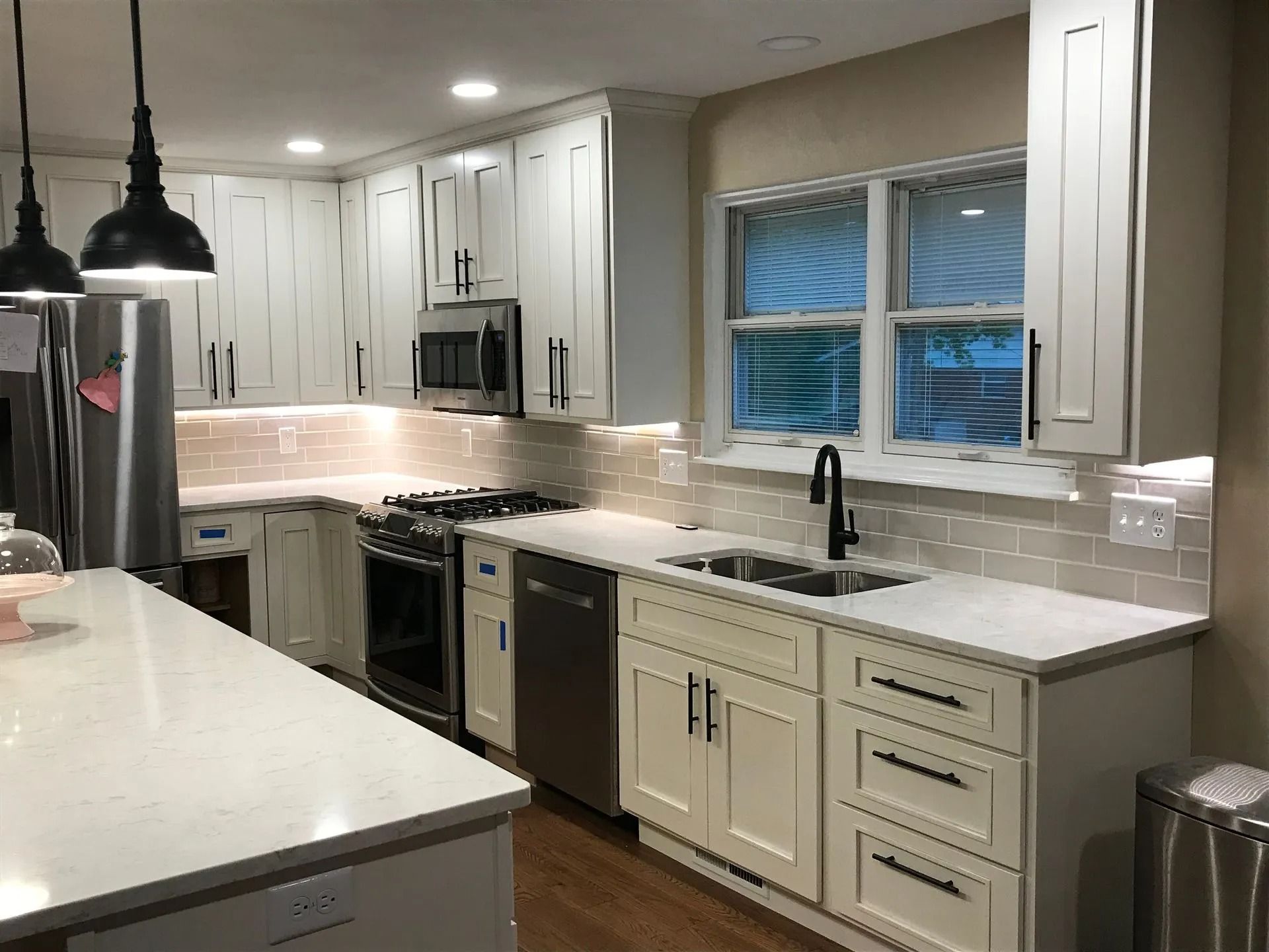 A modern kitchen featuring white cabinets, stainless steel appliances, marble countertops, and a subway tile backsplash.