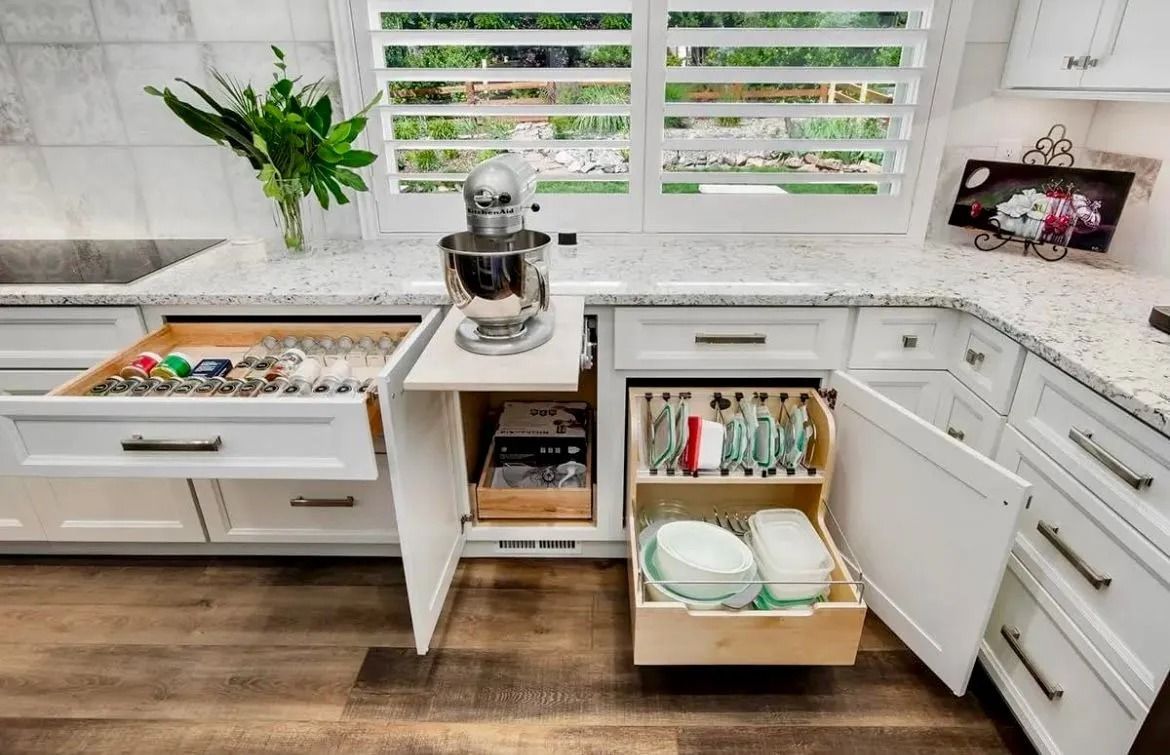 A kitchen countertop featuring a pull-out stand mixer shelf and two base cabinets with open organizational storage drawers.
