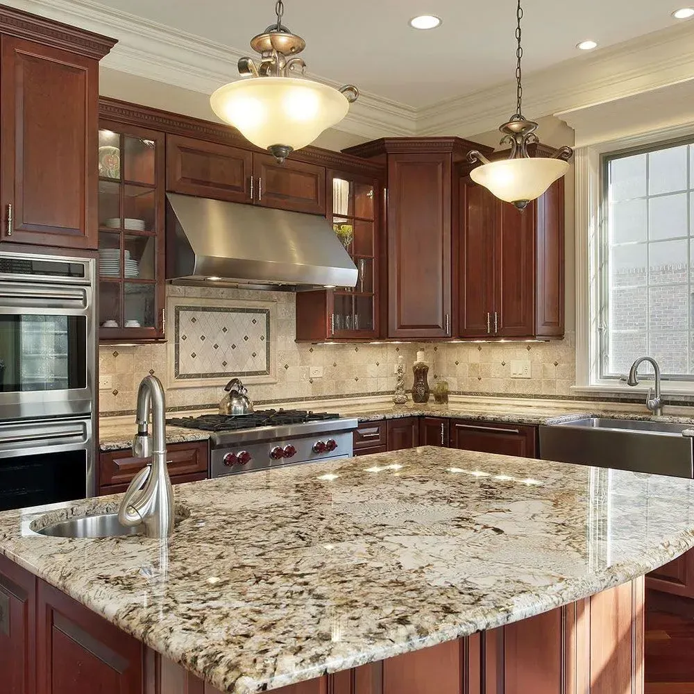 A kitchen featuring dark wood cabinets, a large granite island with a sink, stainless steel appliances, and pendant lights.