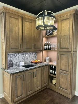 A custom wood wet bar with granite countertops, tiled backsplash, open shelving, and a hanging pendant light.