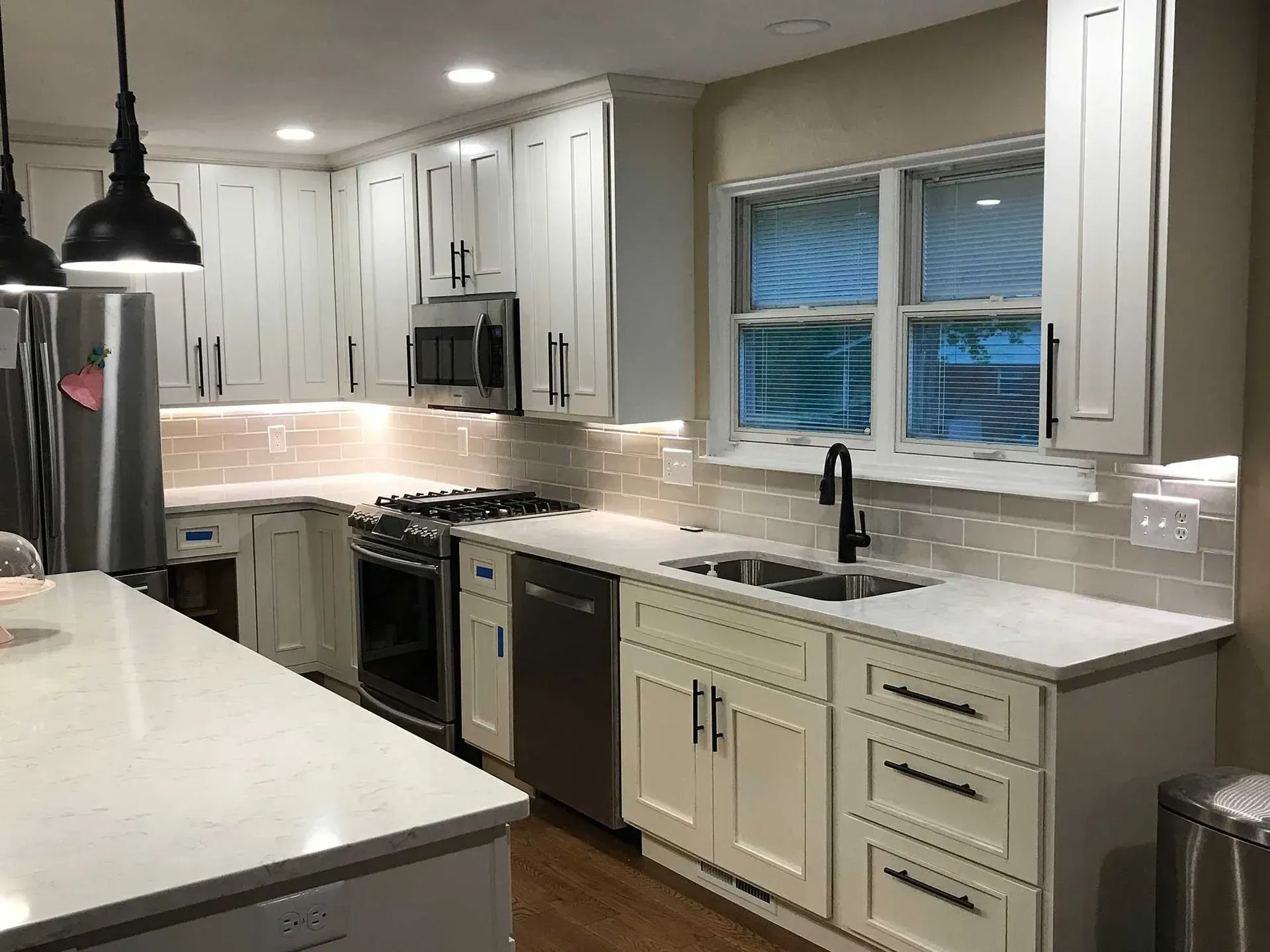 Modern kitchen with white shaker-style cabinets, quartz countertops, subway tile backsplash, and stainless appliances.