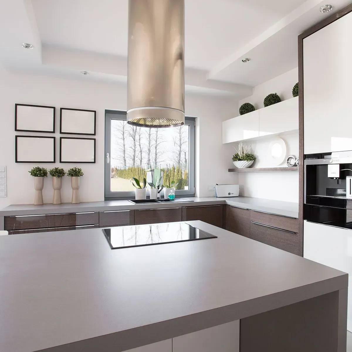 Modern kitchen with a large island, stainless steel hood, white cabinets, and a window with a view.