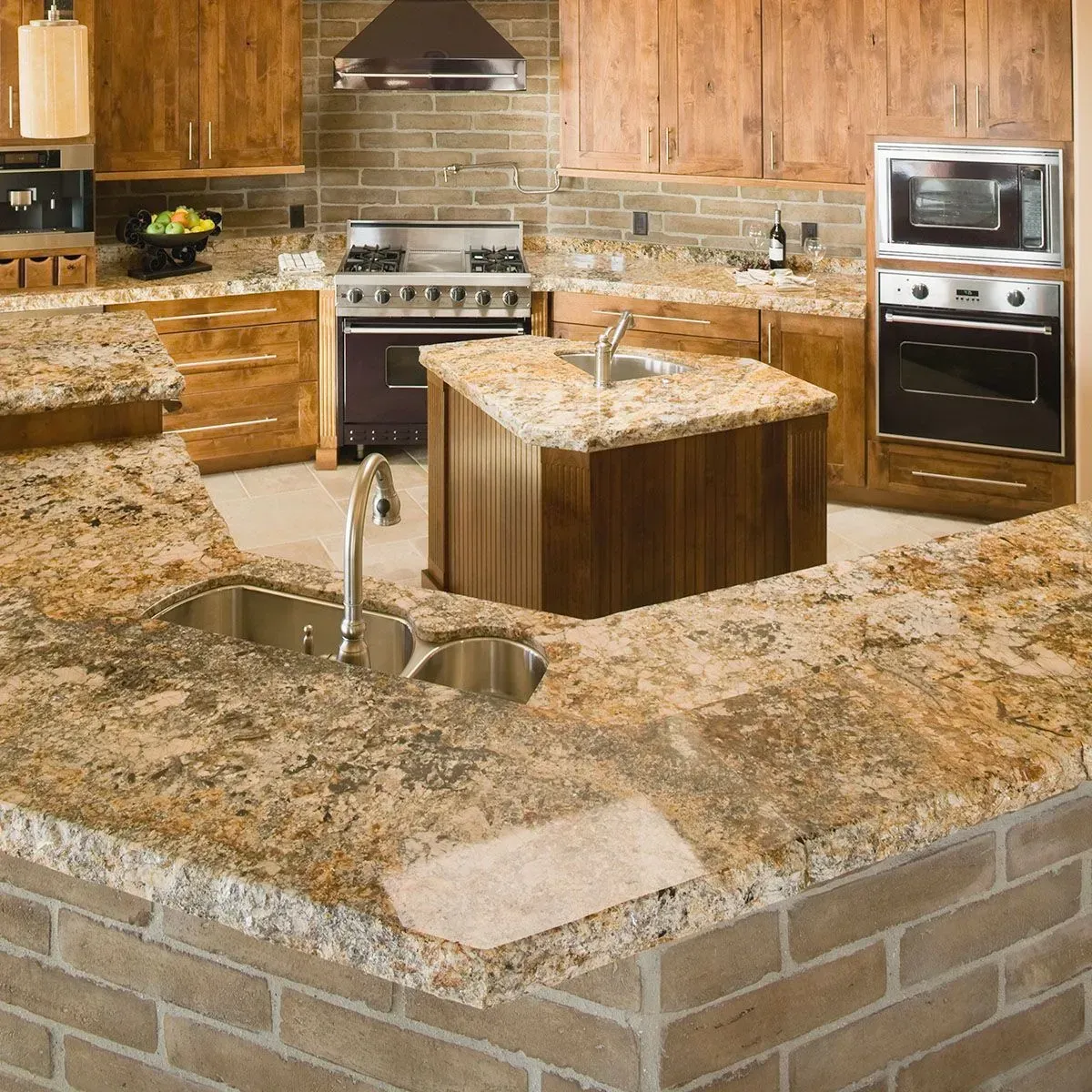 A traditional-style kitchen with natural wood cabinets, granite countertops, a brick base island, and stainless appliances.