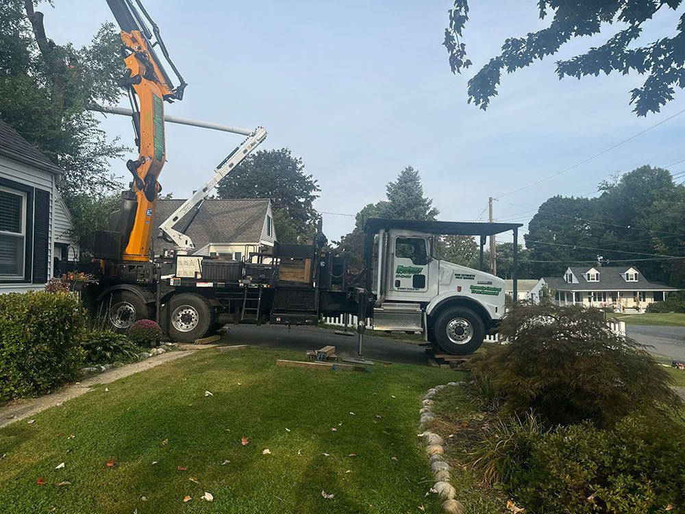 A white truck with a crane on the back is parked in front of a house.