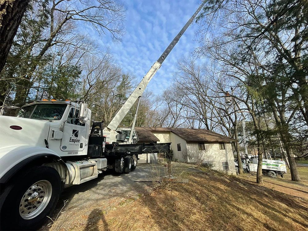 A white truck with a crane attached to it is parked in front of a house.