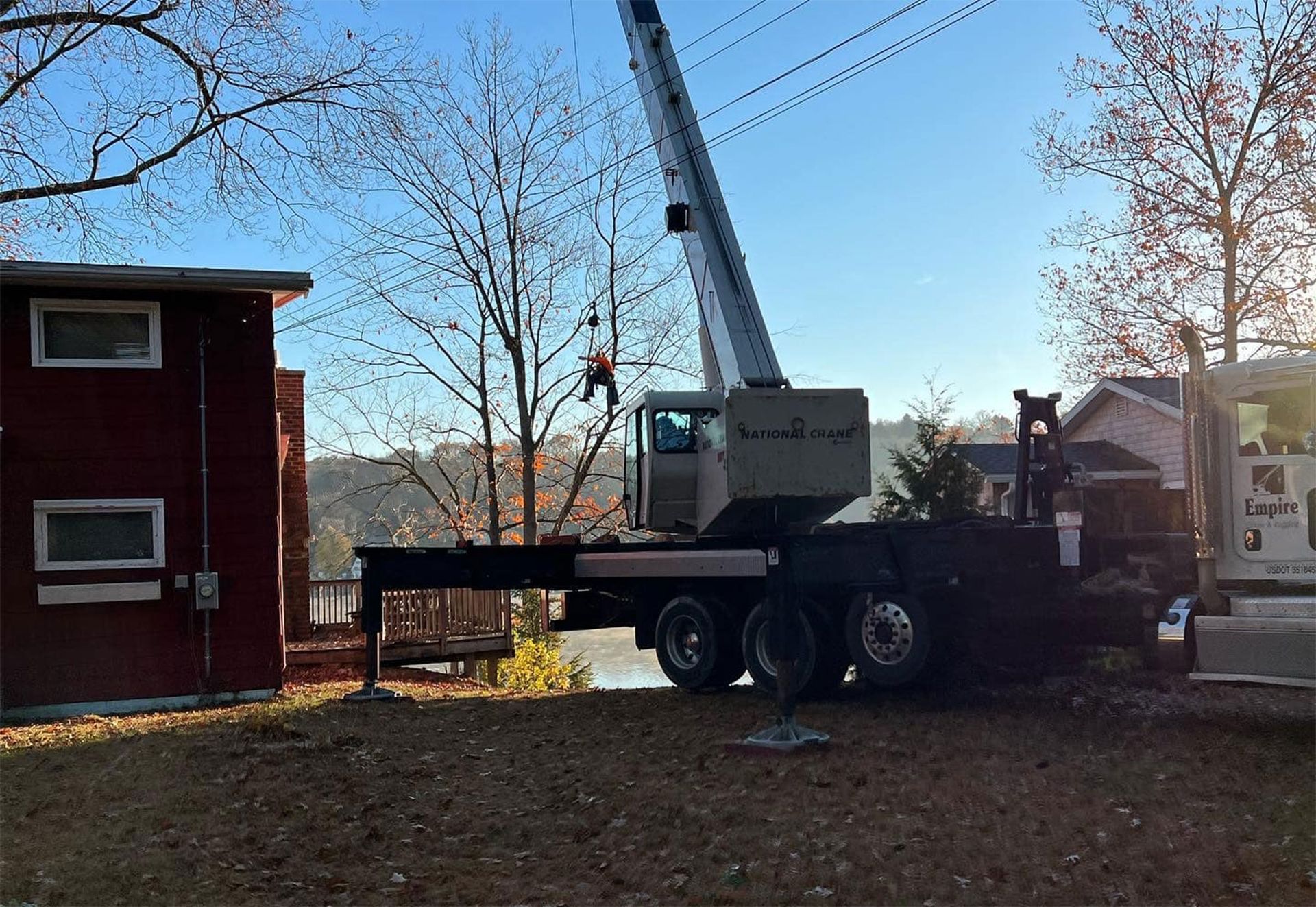 A large crane is parked in front of a red house