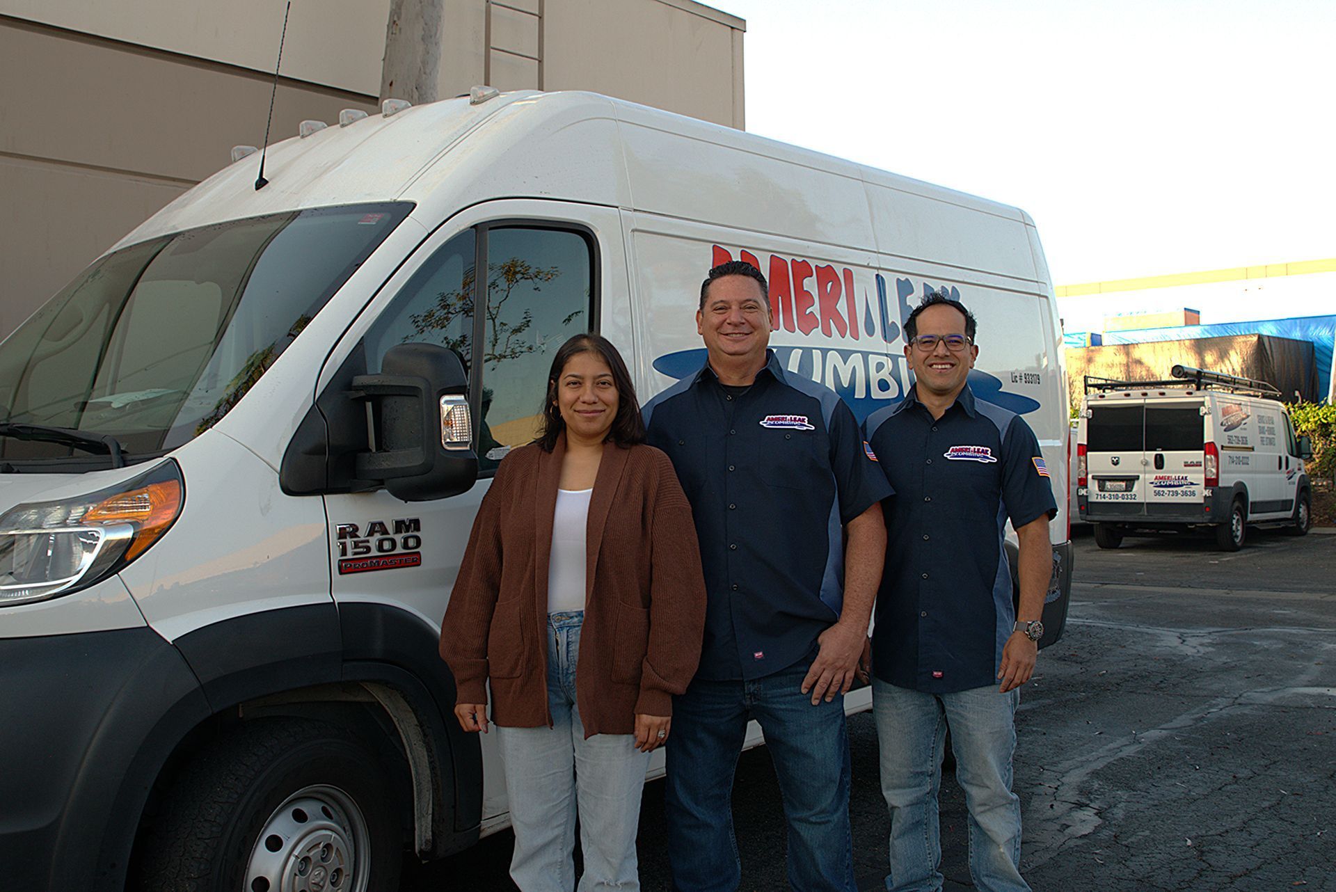 Three people stand in front of a white van with 