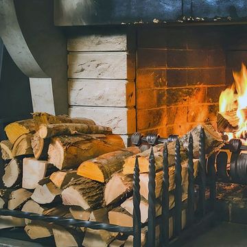 A pile of logs is sitting in front of a fireplace.