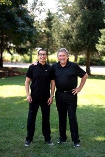 Two men are standing next to each other in a grassy field.