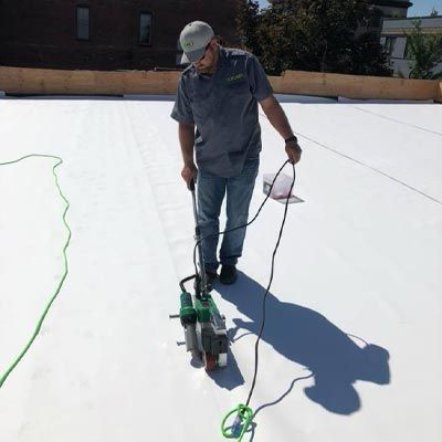 A man is working on a roof with a machine