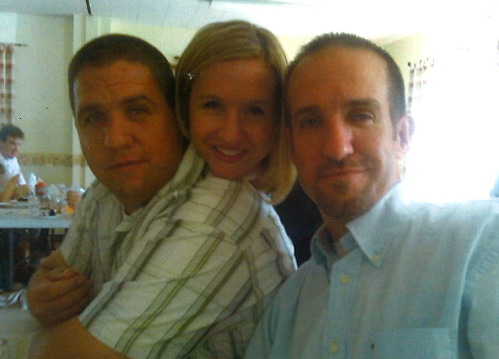 Three people posing closely together indoors, smiling at the camera.