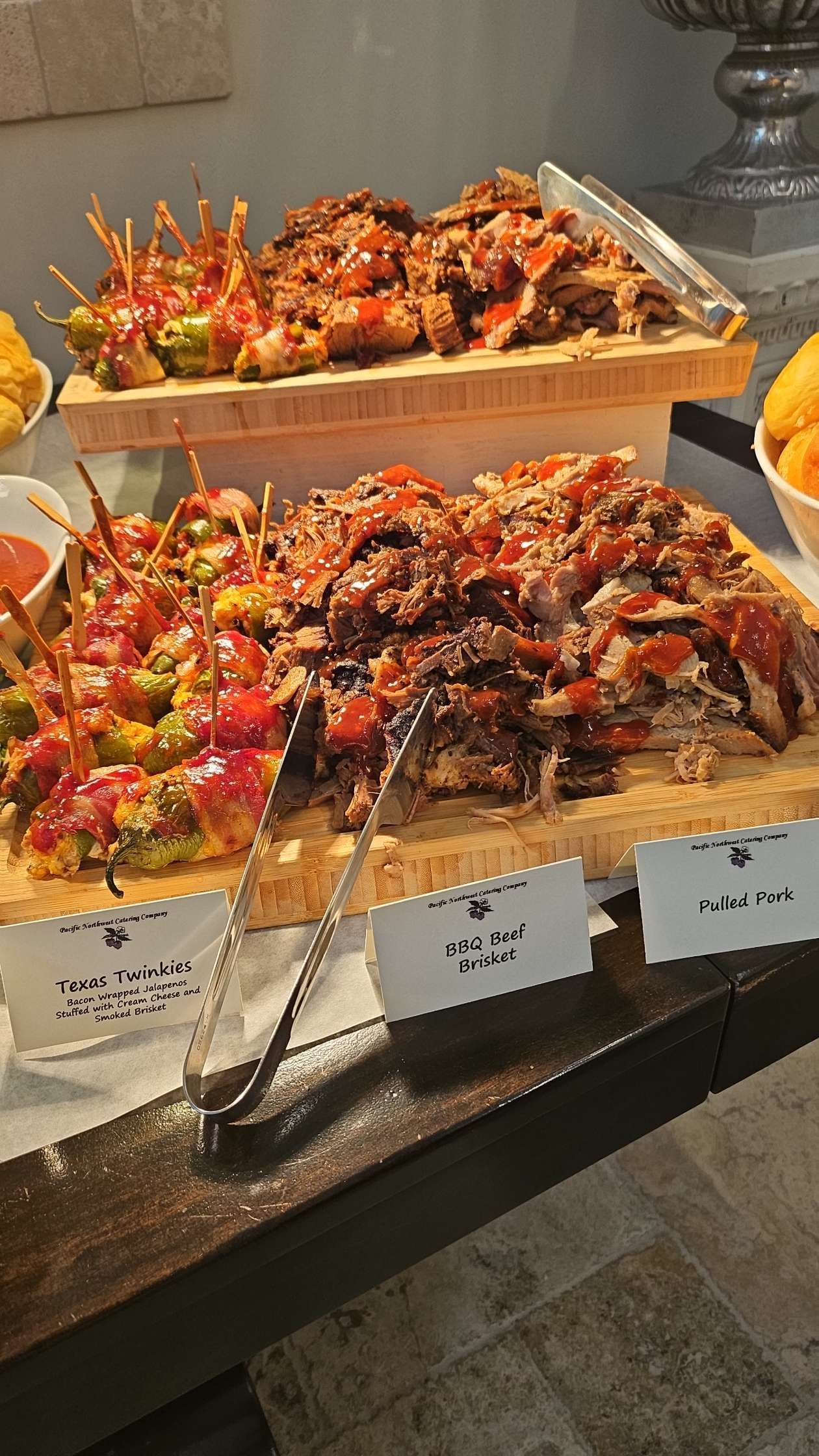 There are many different types of BBQ on the table with a pair of tongs.