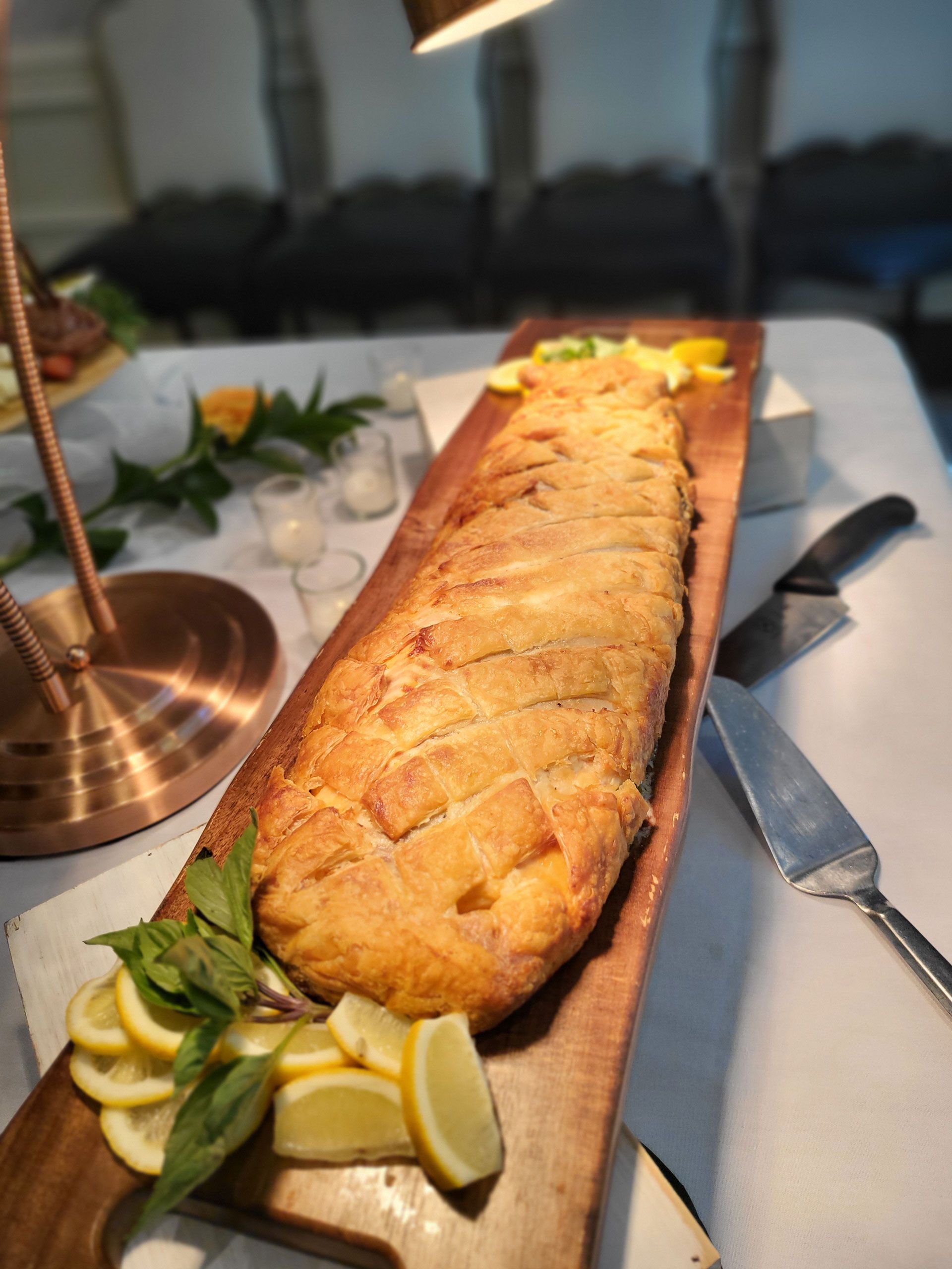 A long piece of food is sitting on a wooden cutting board on a table.
