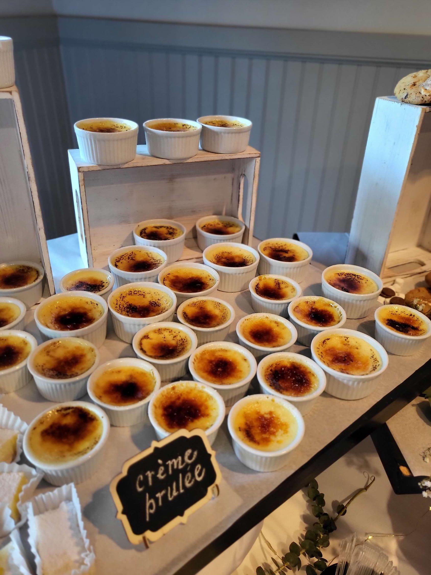 Crème brûlée desserts arranged on a white table. A chalkboard sign reads 
