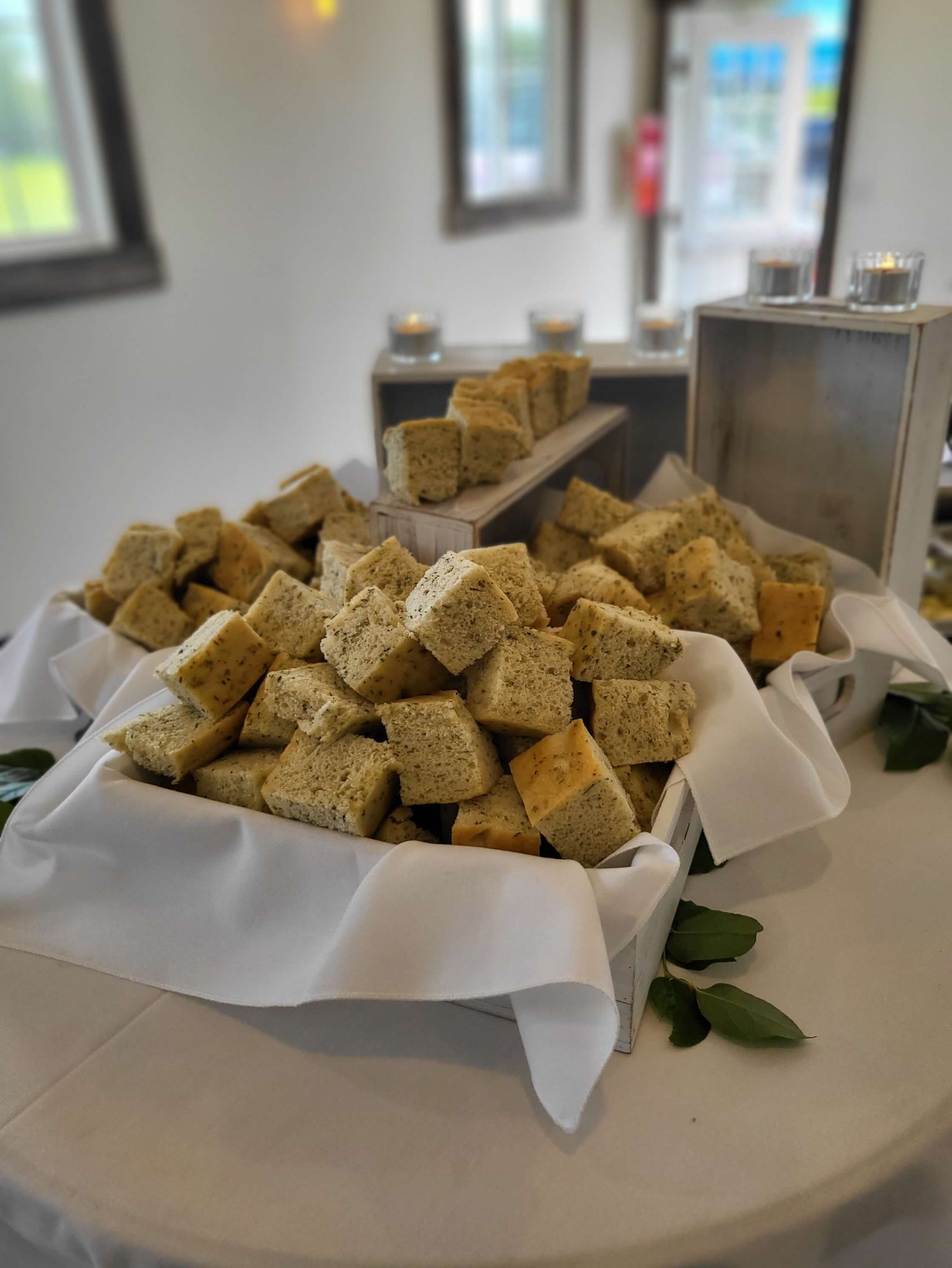 Basket overflowing with cubed bread on a white cloth, set on a table. Blurred background of a room.