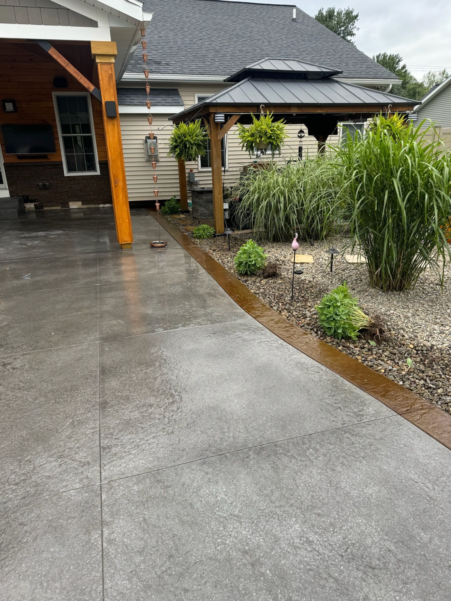 A concrete driveway leading to a house with a gazebo in the background.