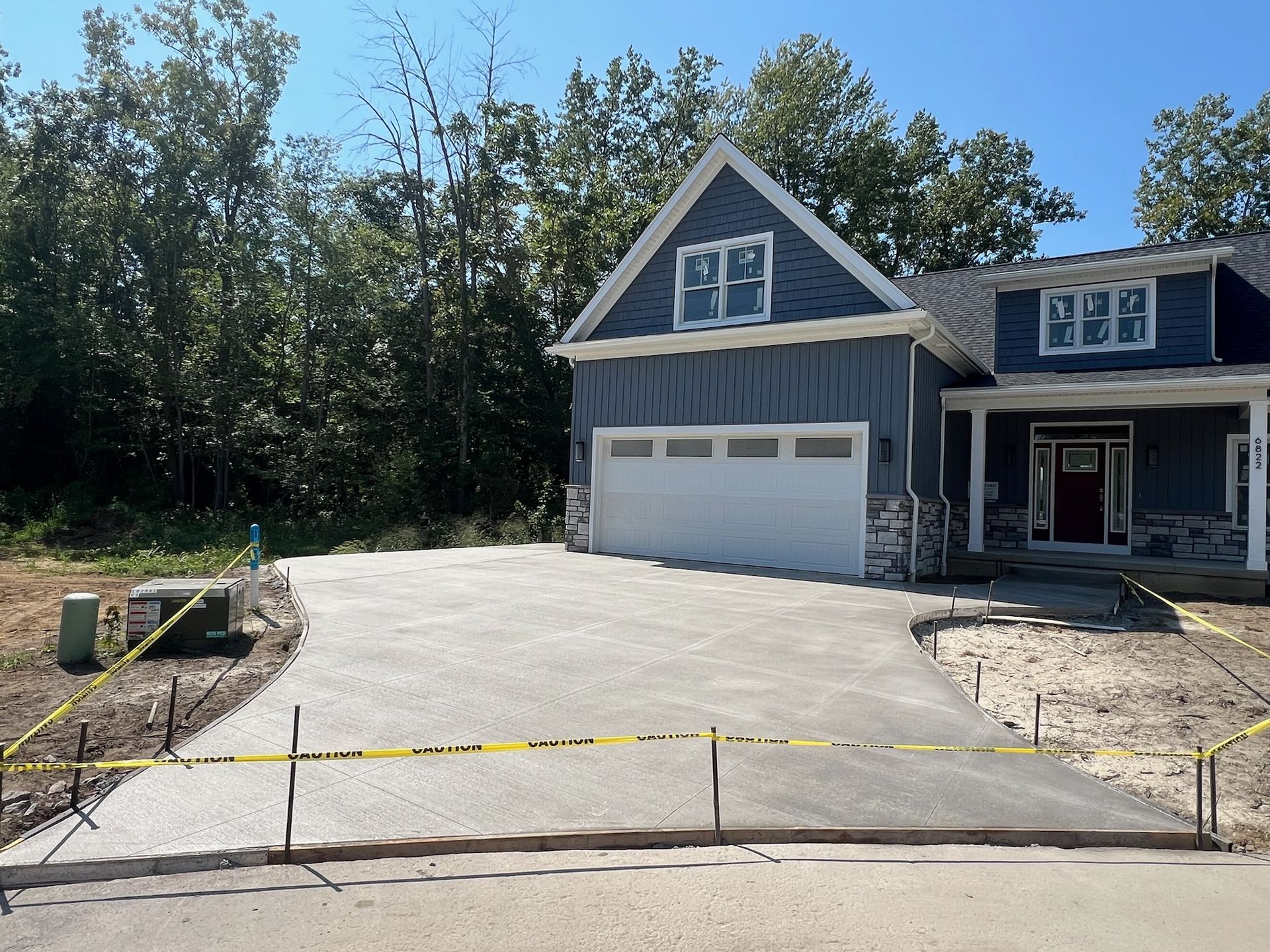 A blue house with a white garage door and a concrete driveway