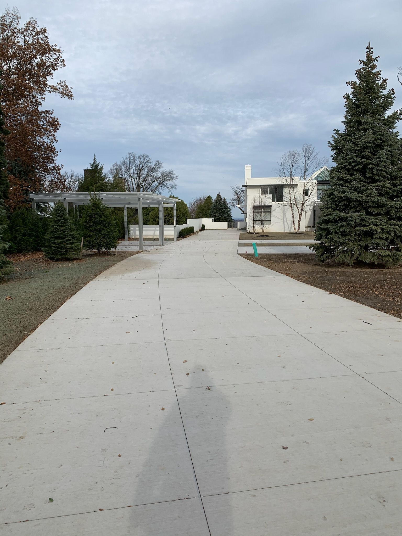 A concrete driveway leading to a white house
