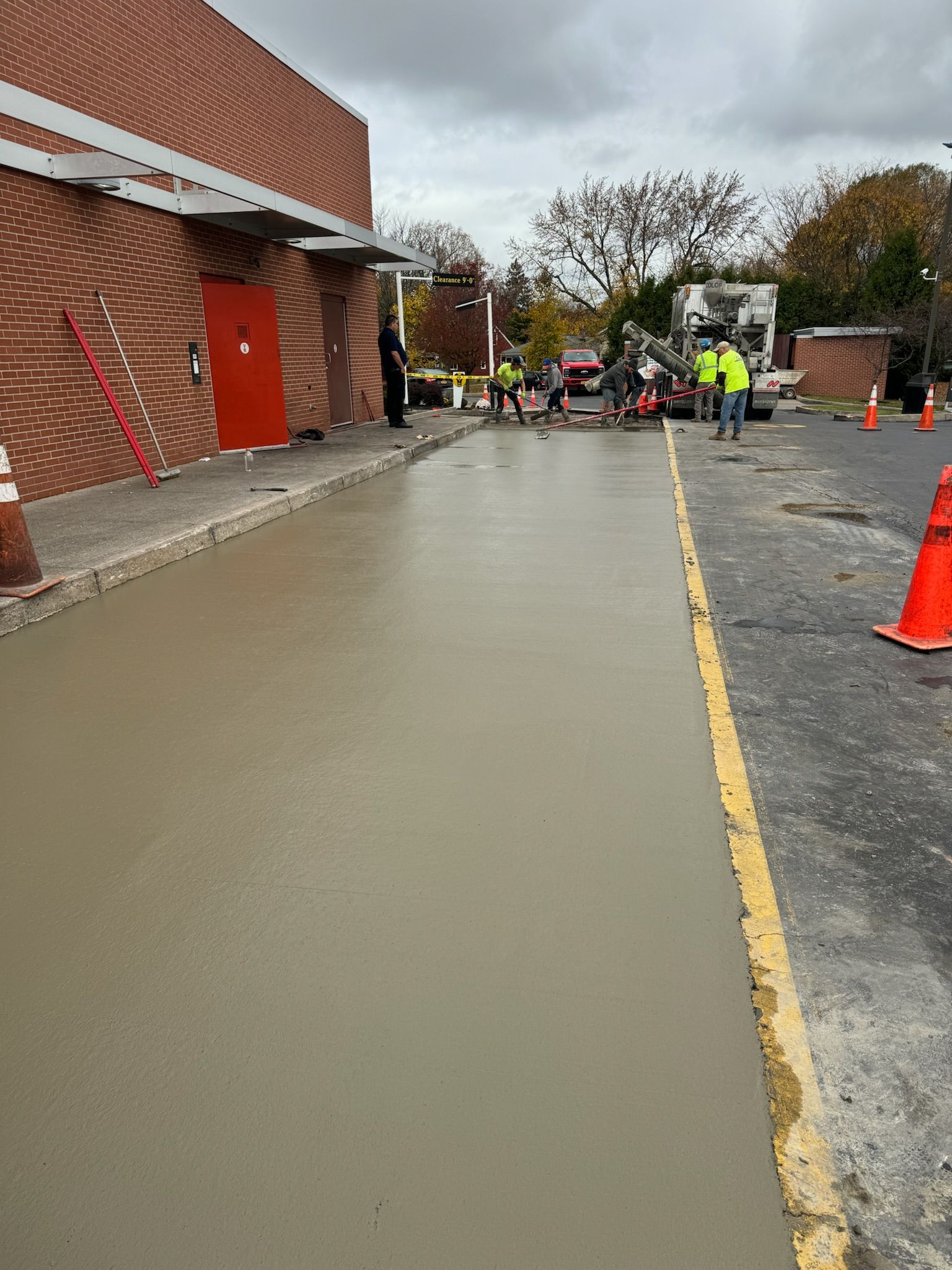 A concrete driveway is being poured in front of a brick building.