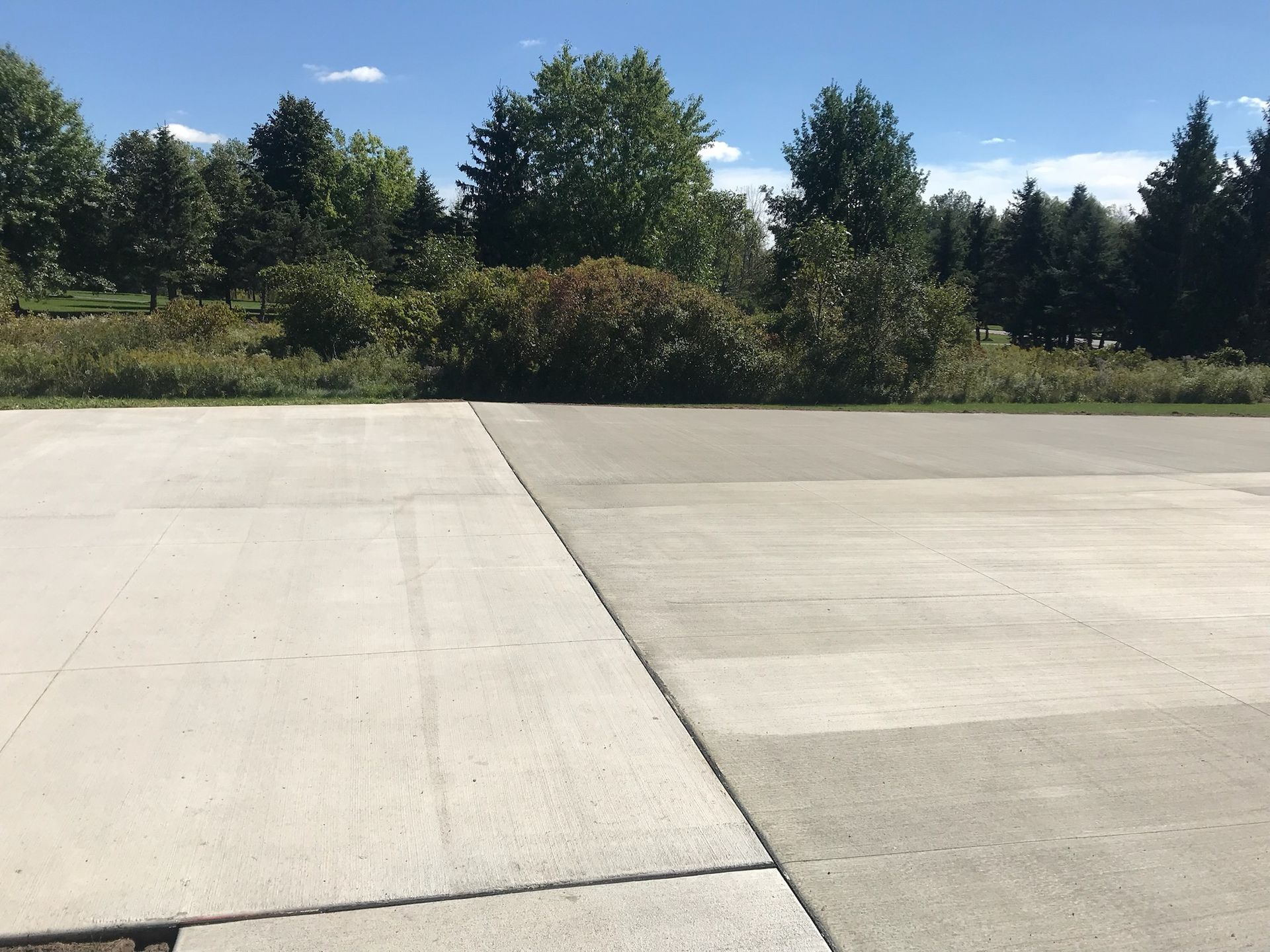 A concrete driveway with trees in the background