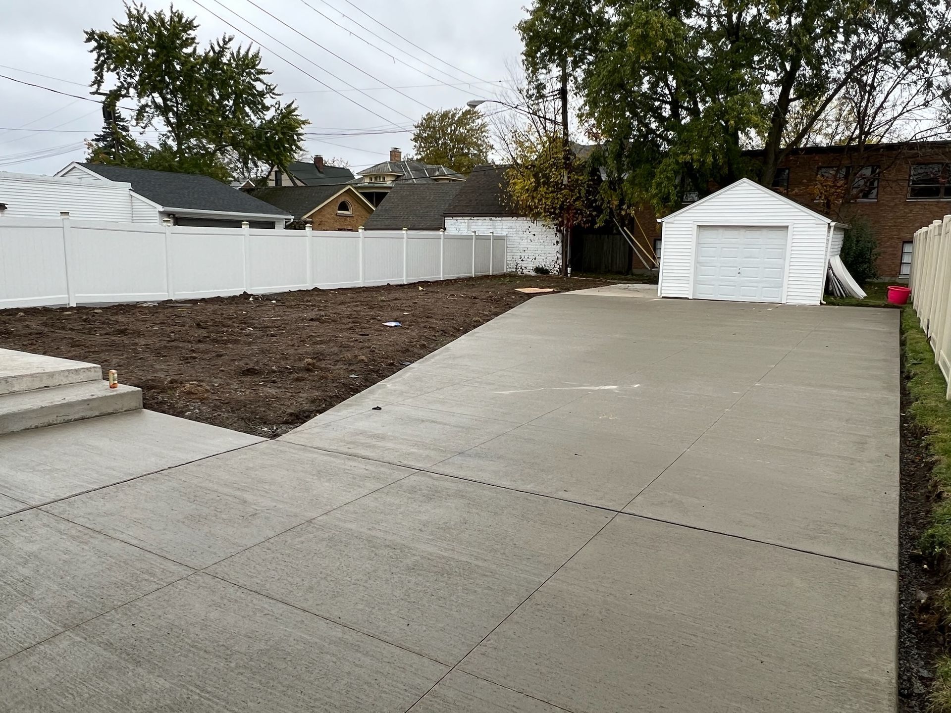 A concrete driveway leading to a garage with a white tent in the background
