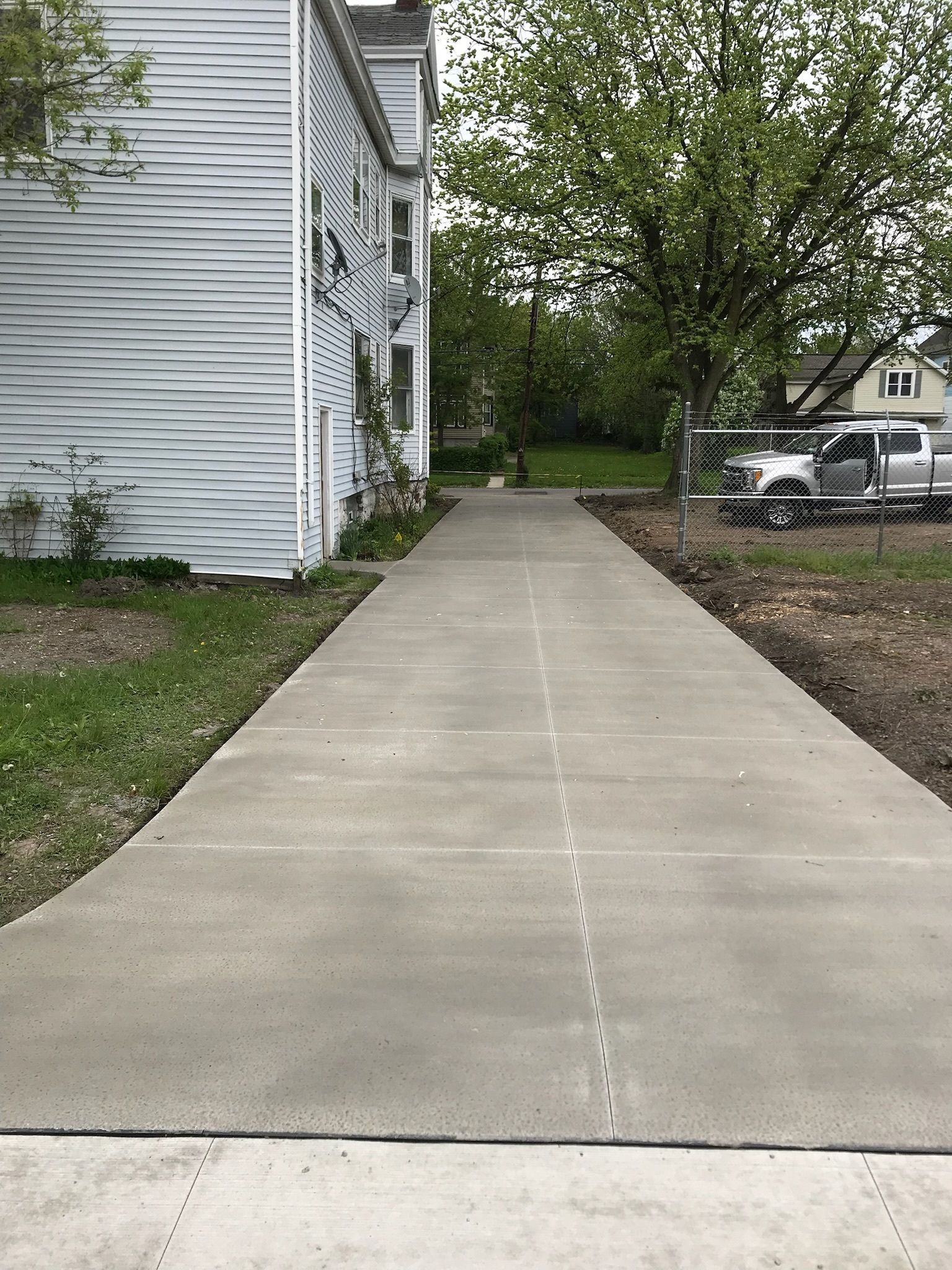 A concrete walkway leading to a white house.