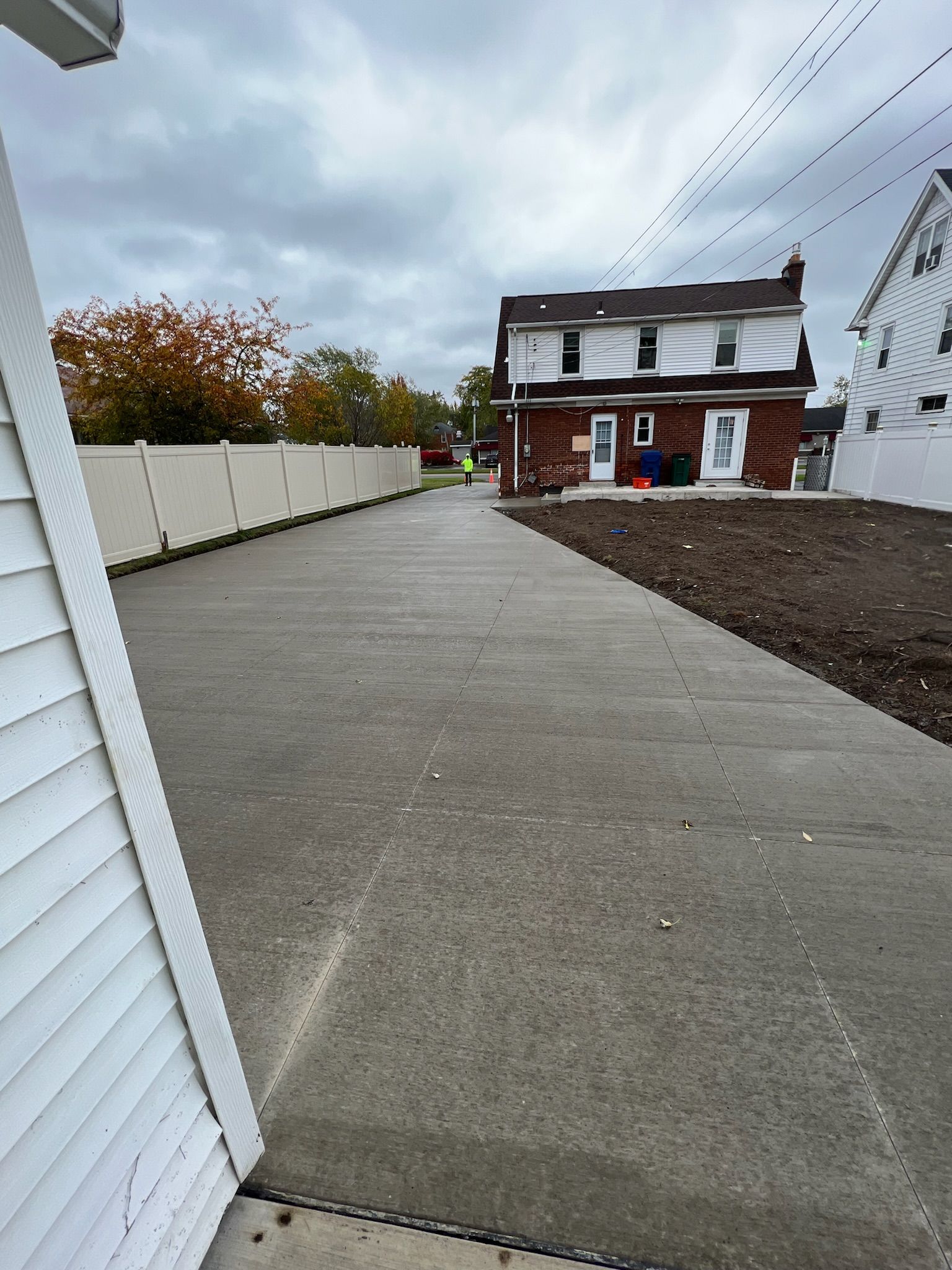 A concrete walkway leading to a house on a cloudy day.