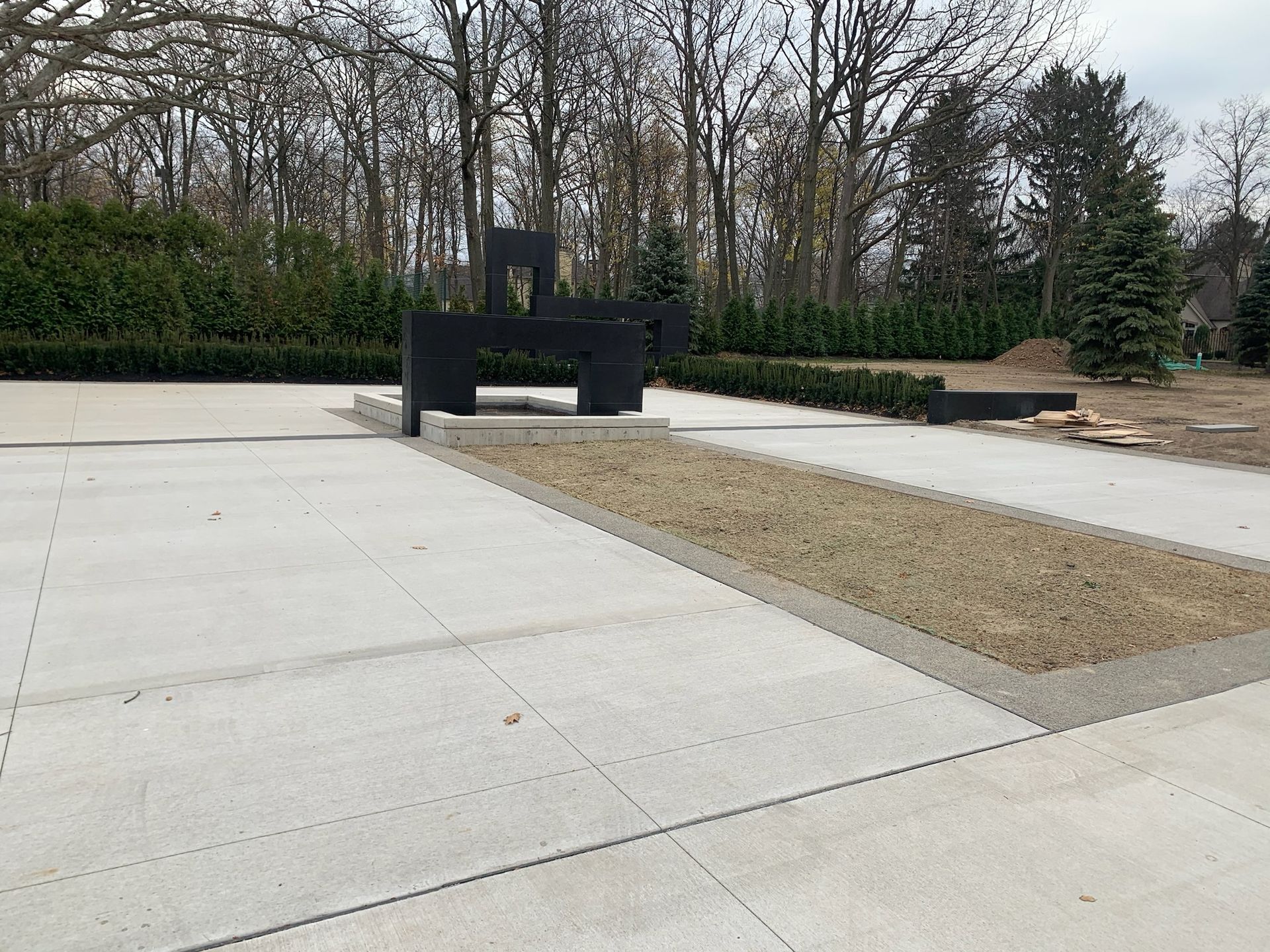A concrete walkway with a black sculpture in the middle