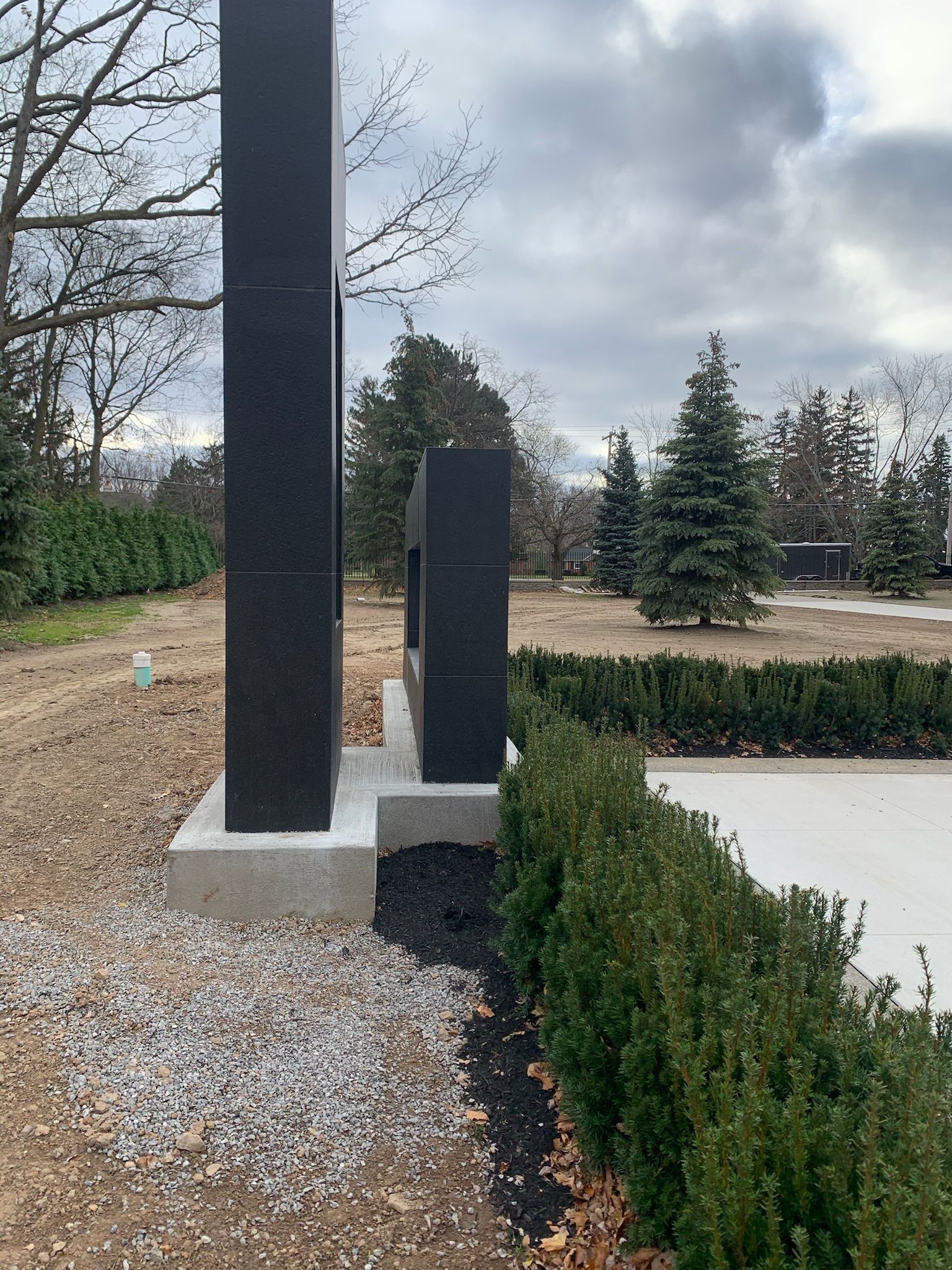 A statue is sitting in the middle of a field next to a bush.