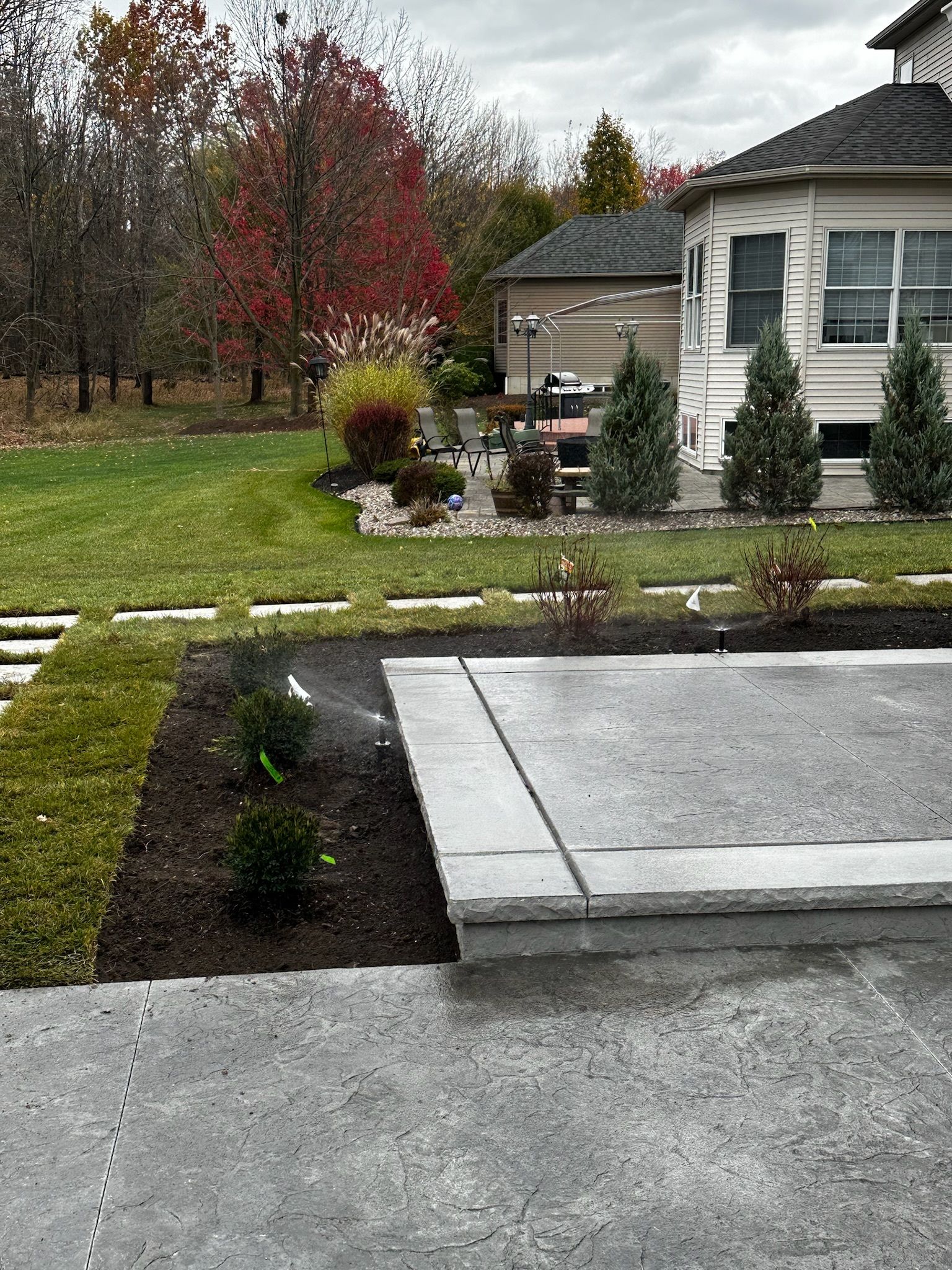 There is a concrete patio in the backyard of a house.