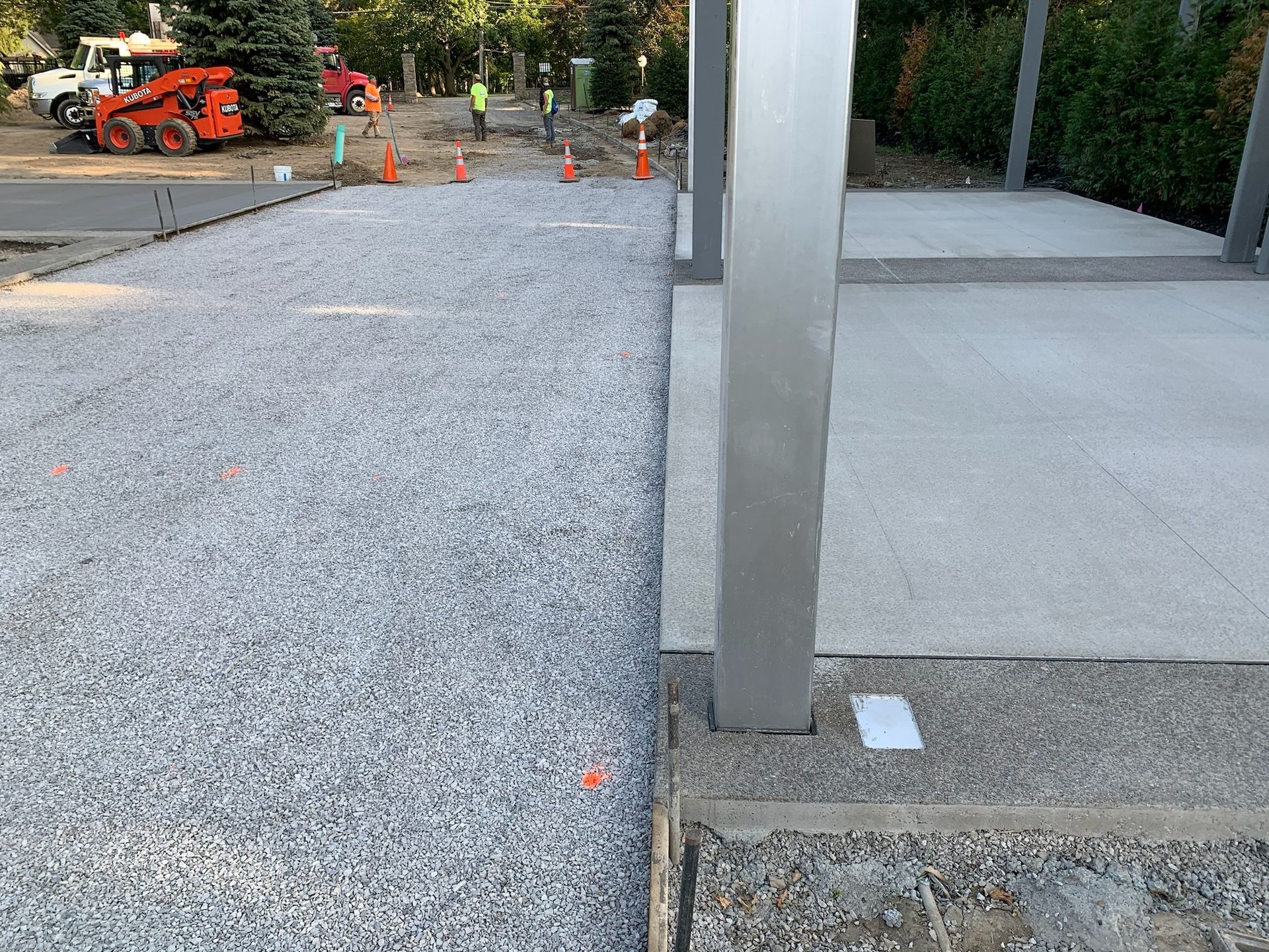 A gravel driveway is being built next to a concrete walkway.