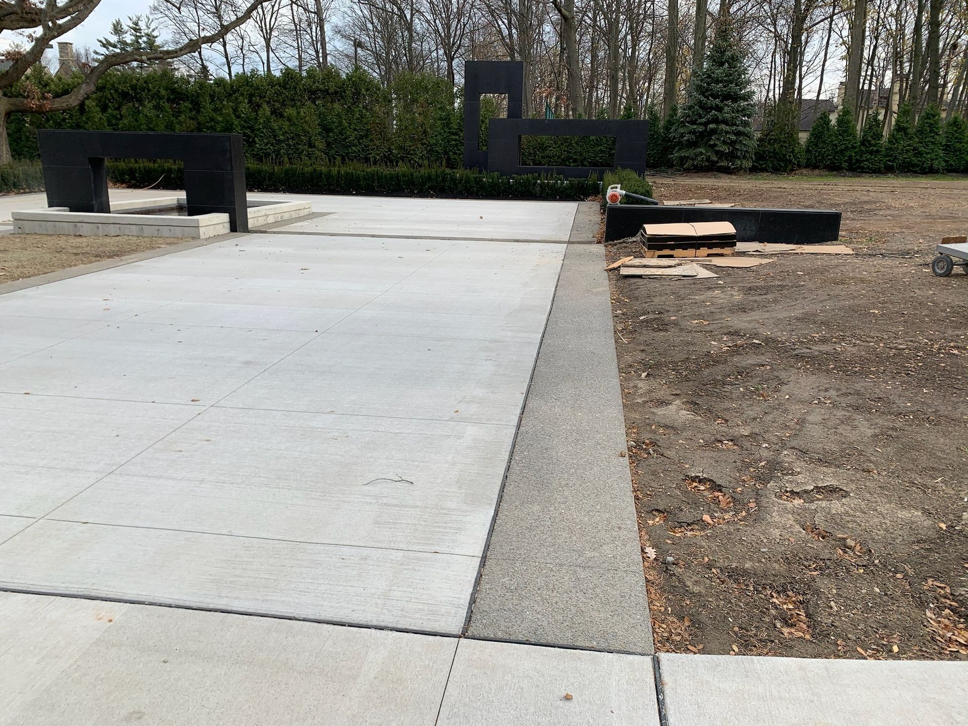 A concrete walkway in a park with trees in the background