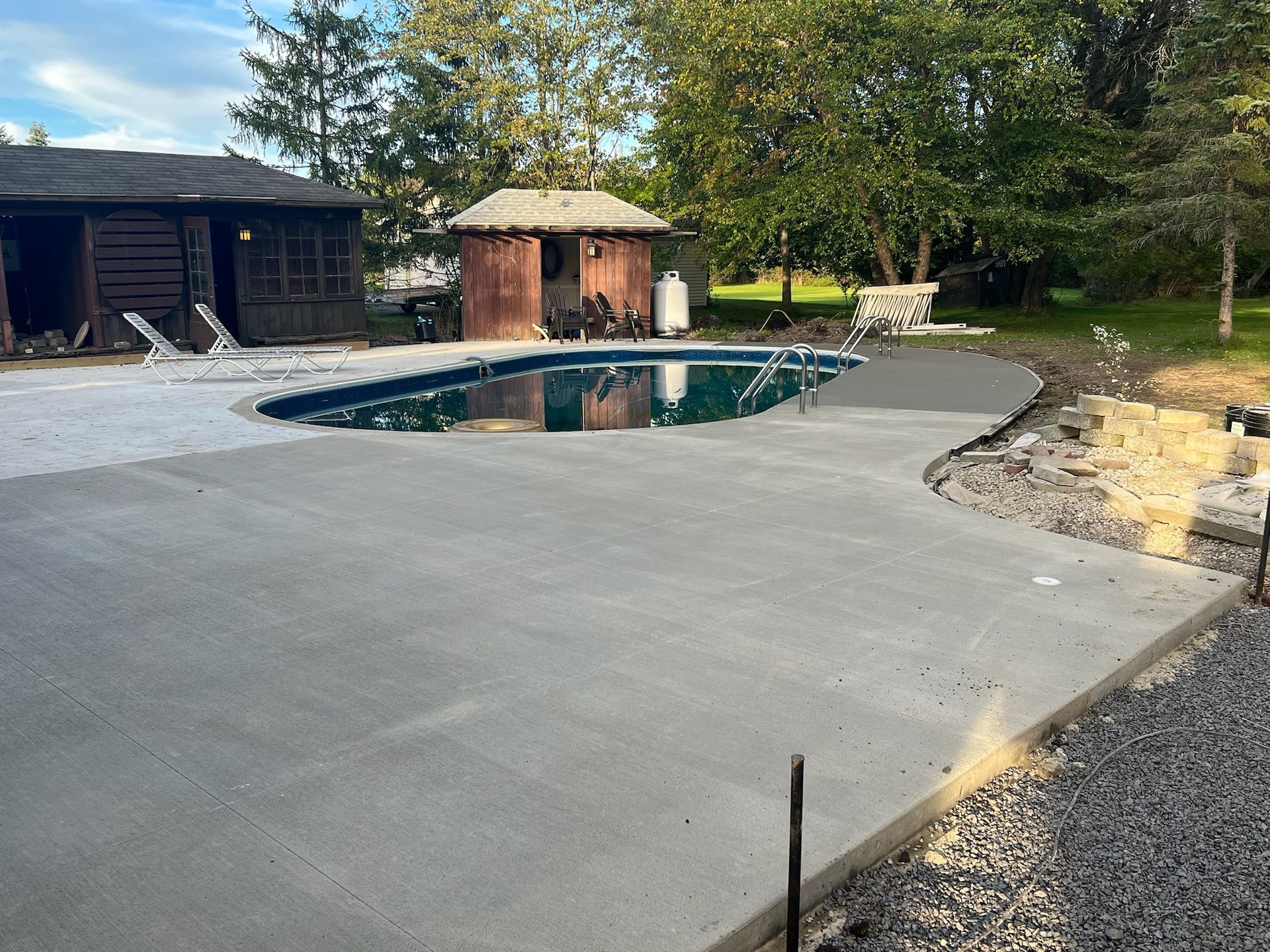 A concrete patio with a swimming pool in the background