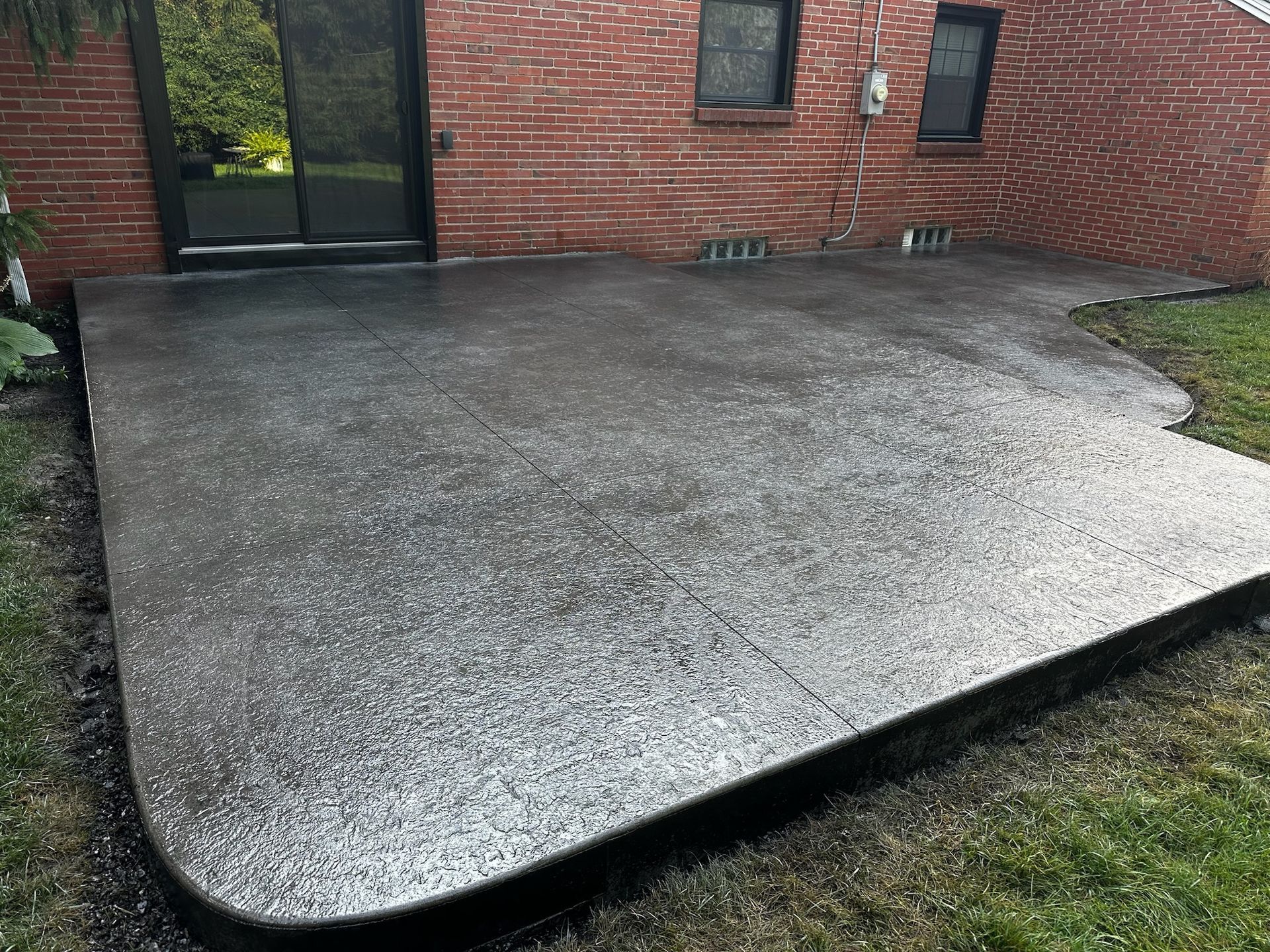 A brick house with a concrete patio in front of it.