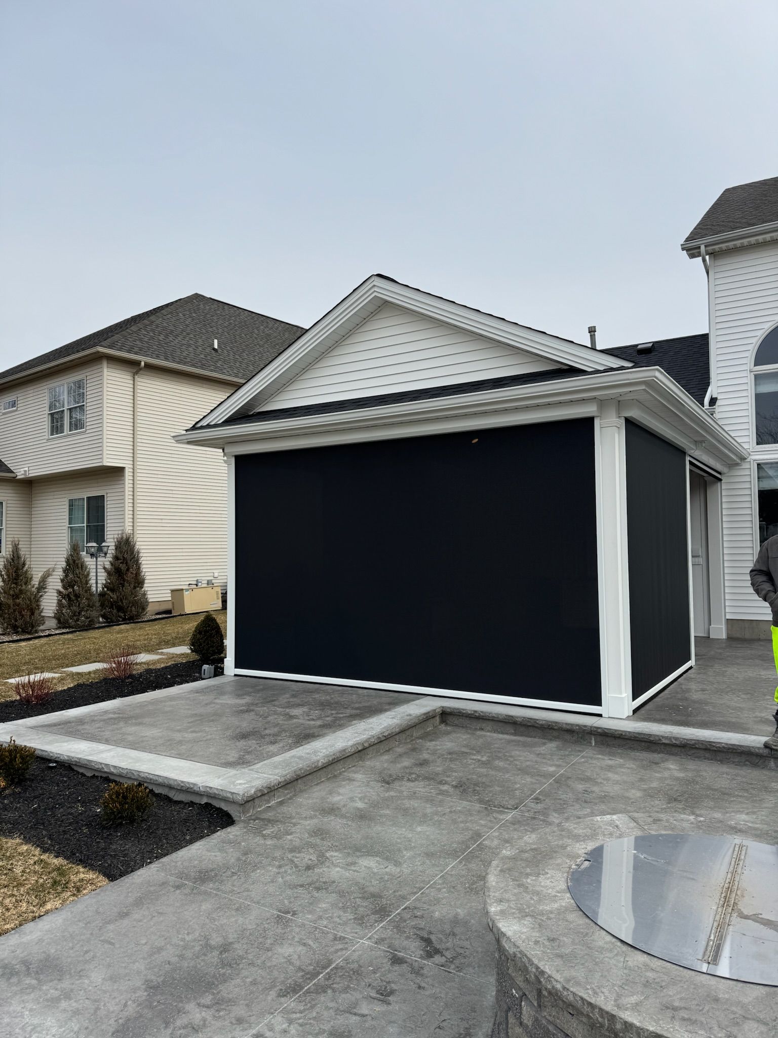 A man is standing in front of a house with a black garage door.