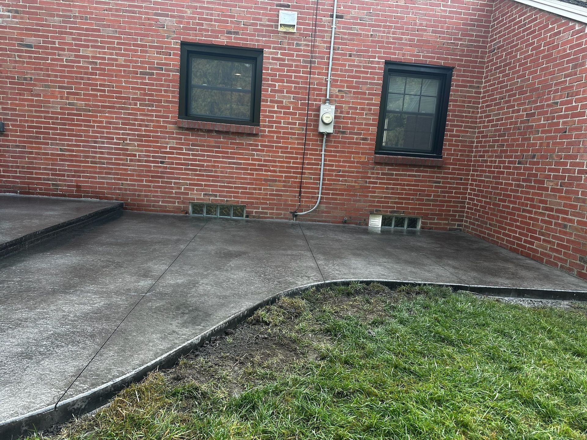 A brick building with a concrete walkway in front of it.