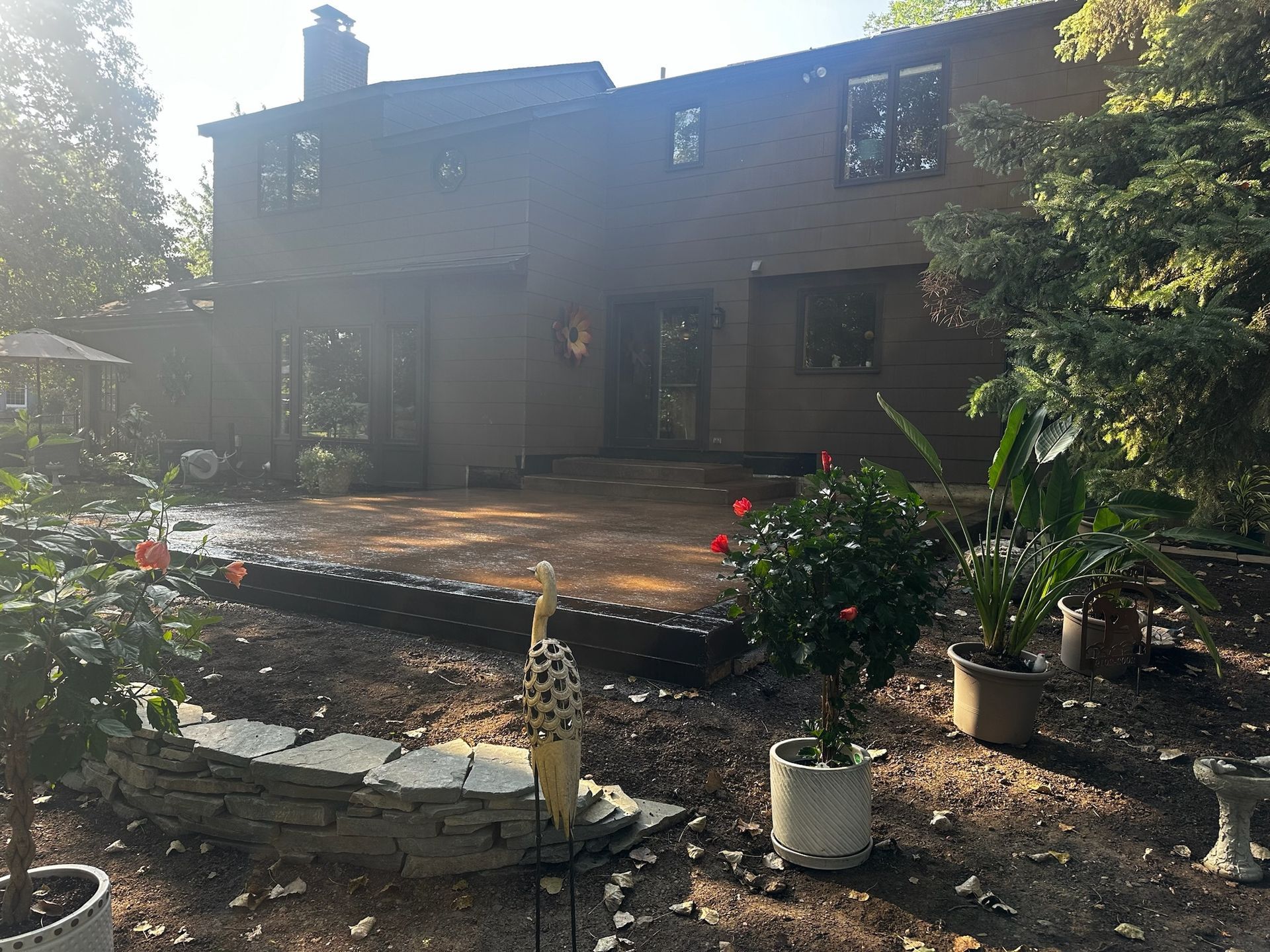 A large brick house with a patio in front of it surrounded by potted plants.