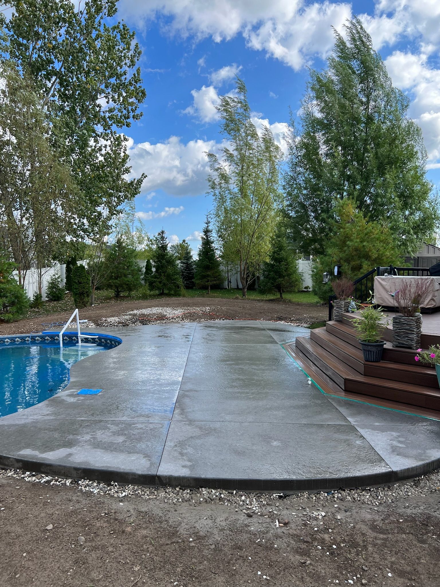 A large concrete patio with a swimming pool in the background.