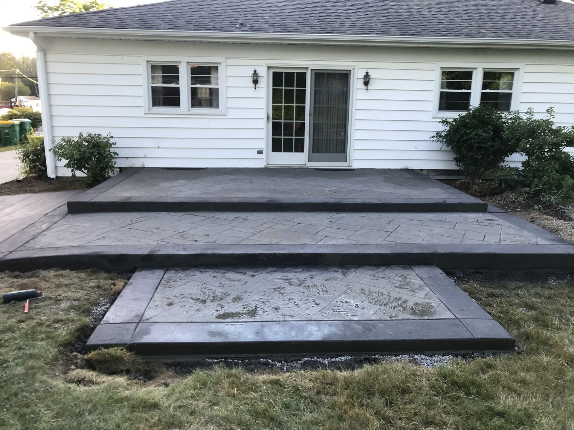 A white house with a concrete patio in front of it.