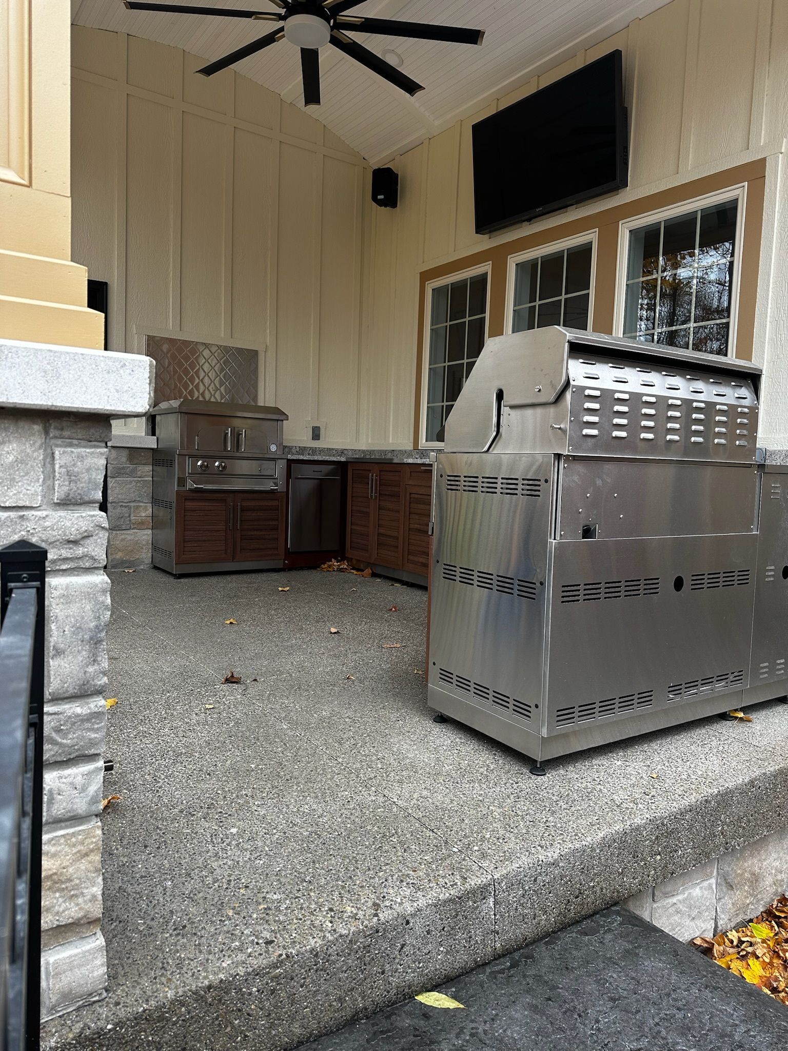 A stainless steel grill is sitting on the side of a patio.