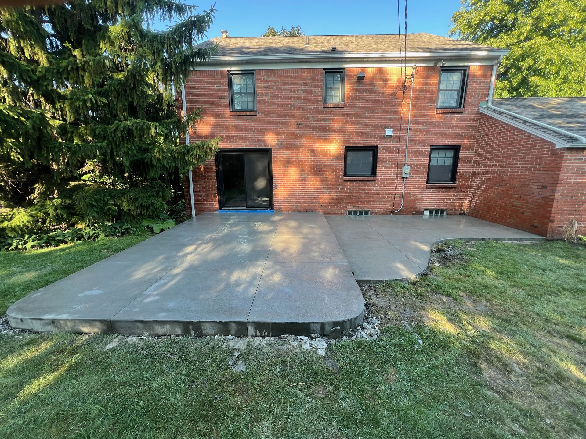 A brick house with a concrete driveway in front of it.