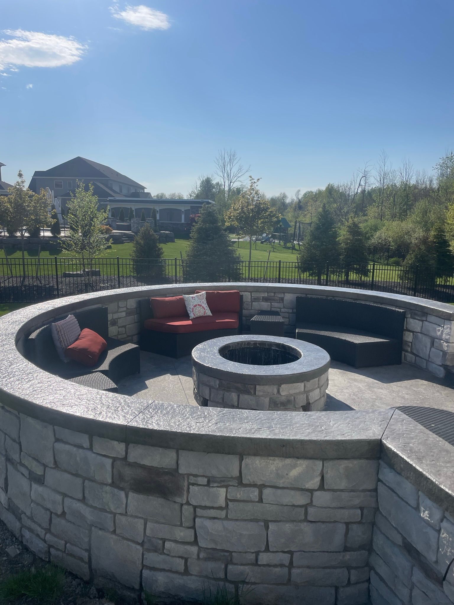 There is a fire pit in the middle of the patio surrounded by furniture.
