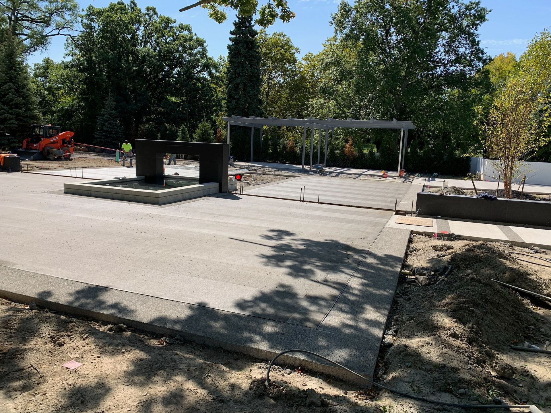 A concrete driveway is being built in a park with trees in the background.