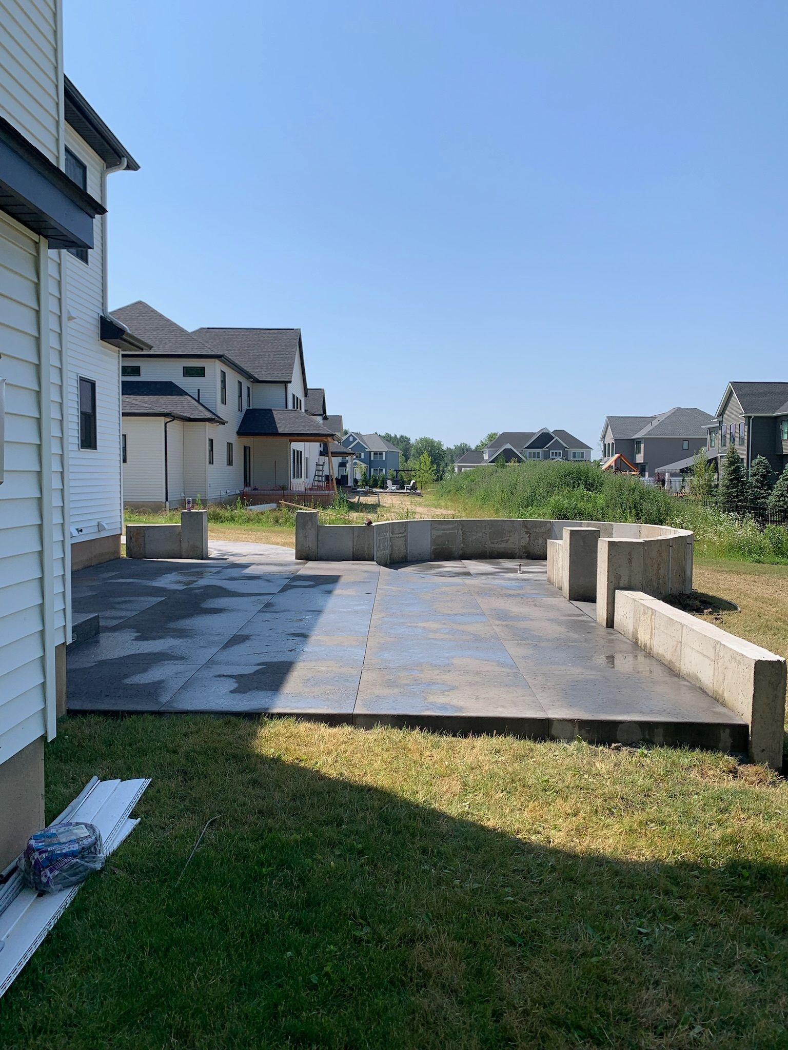 There is a concrete patio in the backyard of a house.