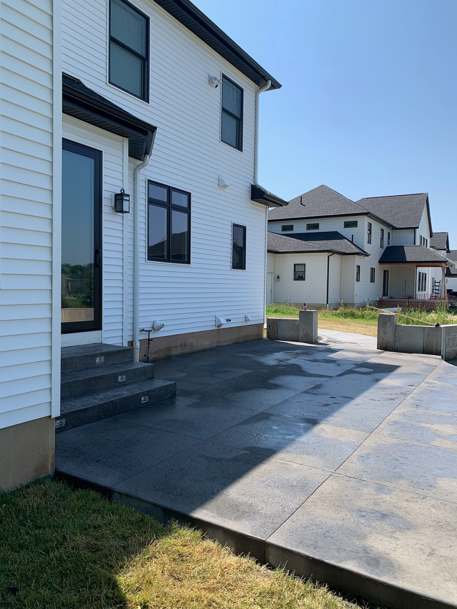 A white house with a concrete patio in front of it.