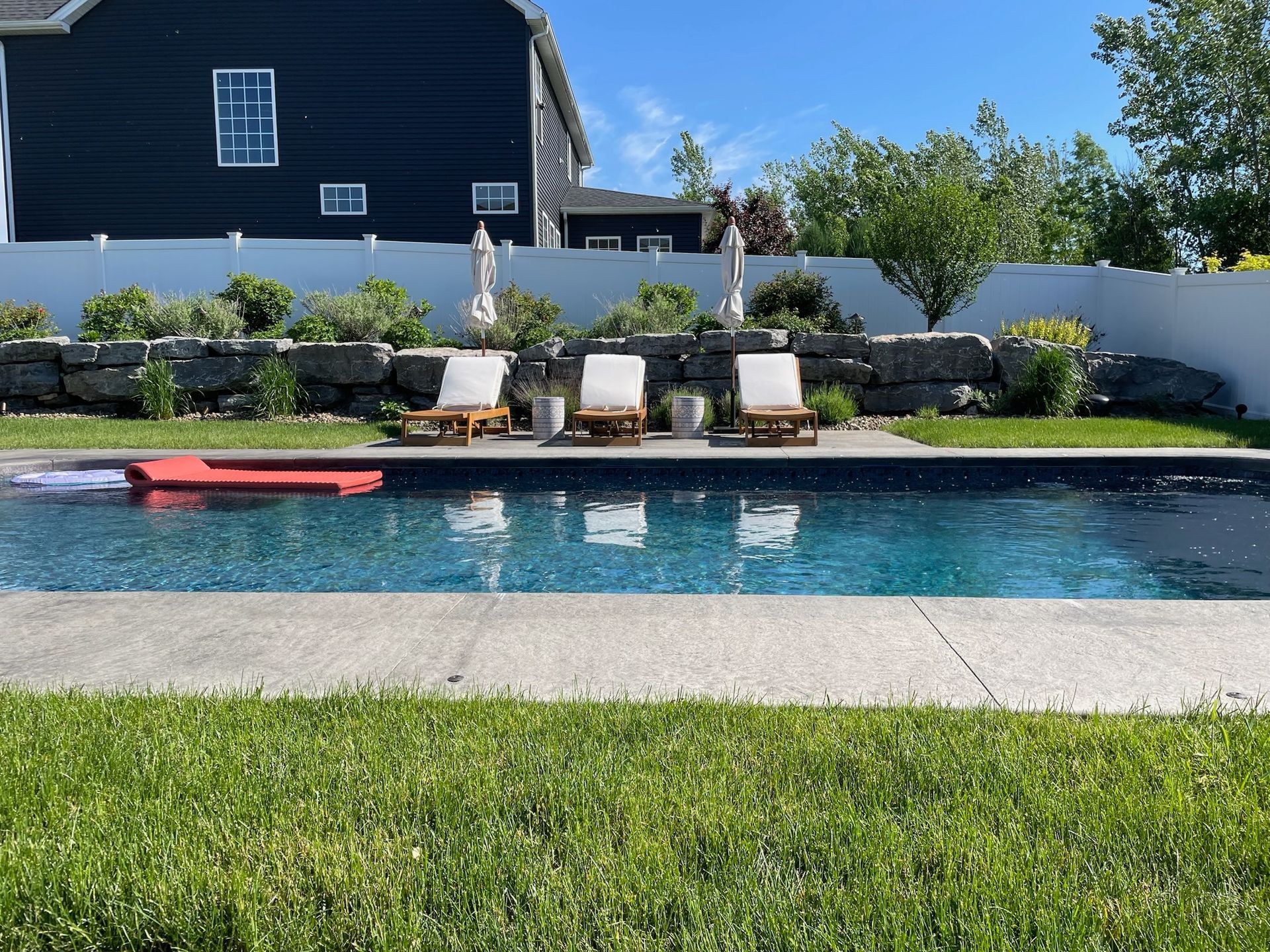 A large swimming pool surrounded by chairs and umbrellas