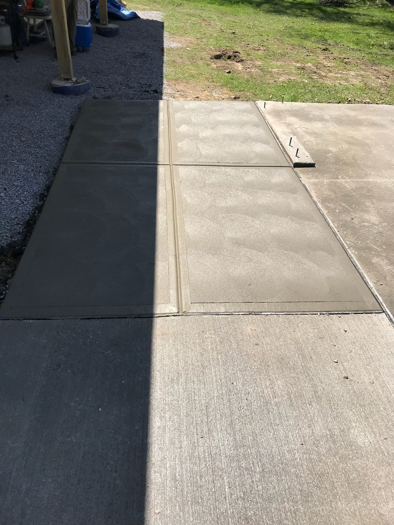 A shadow of a person is cast on a concrete sidewalk.